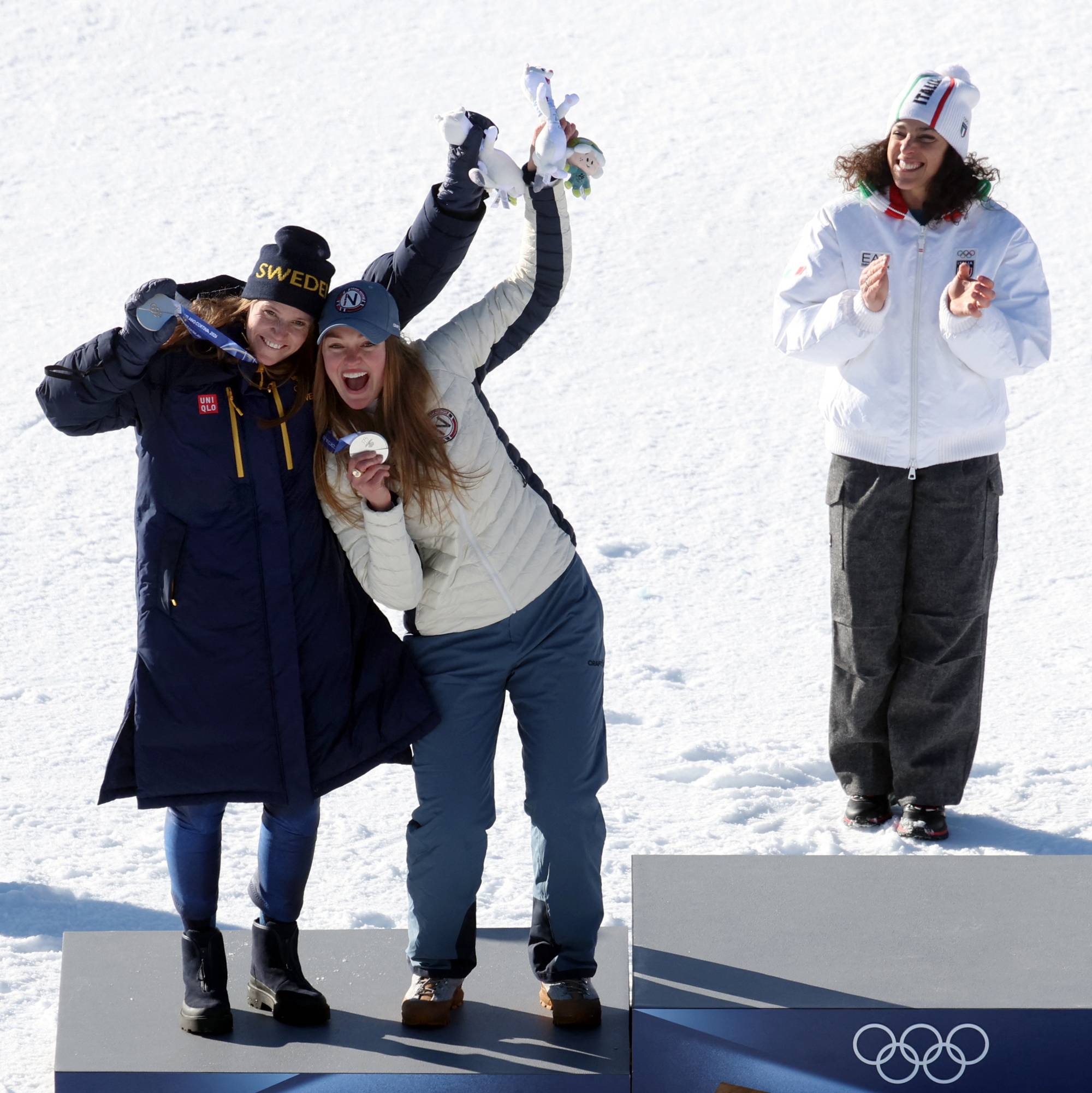 Utøvere på seierspallen etter skirenn. To kvinner jubler med medaljer, mens en kvinne står ved siden. (Bildebeskrivelsen er laget av en KI-tjeneste)