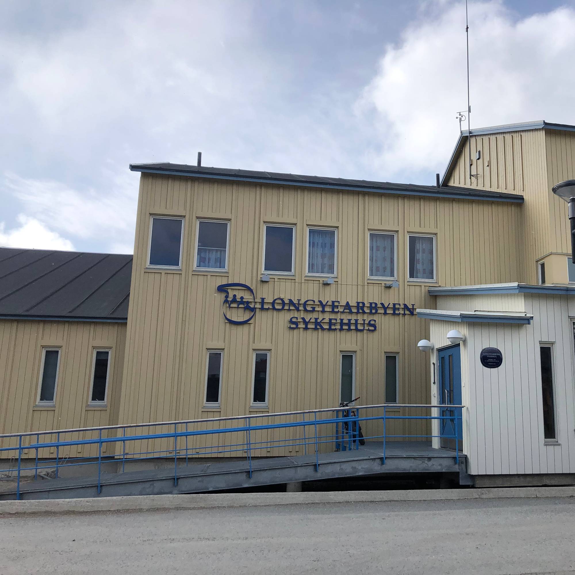 En lysegult bygg, med blå skrift hvor det står Longyearbyen sykehus. 
