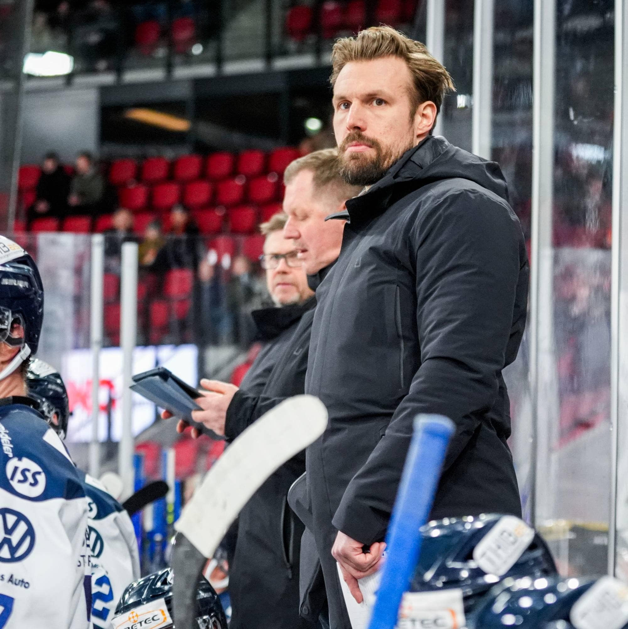 en mann som står på en hockeybane sammen med andre spillere