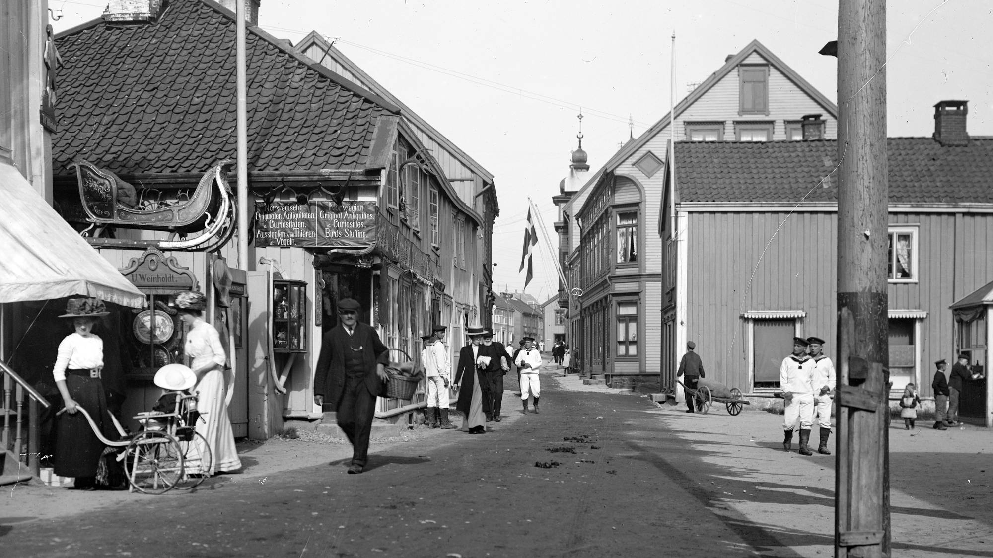 Molde sentrum rundt 1900, grus i hovudgata, tre marinegaster og butikkar som sel fugleutstopping.