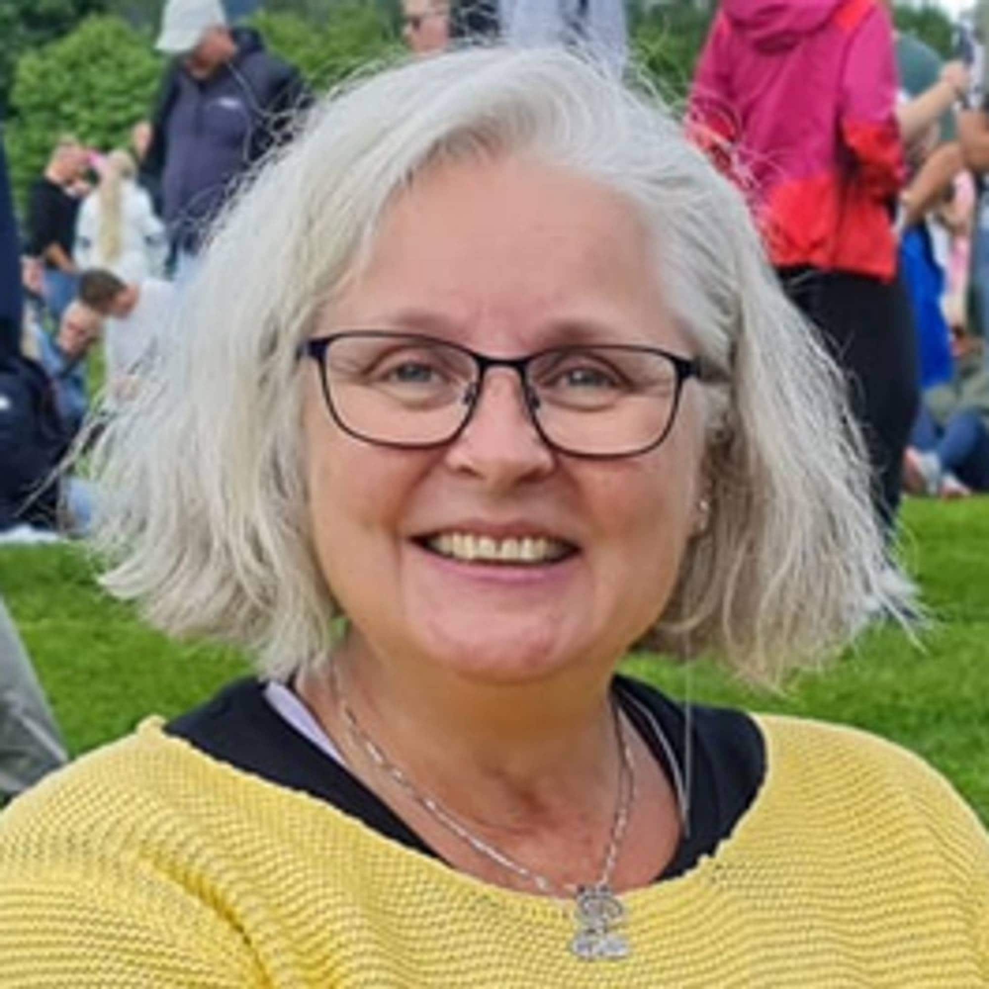 En kvinne med briller som smiler (Bildebeskrivelsen er laget av en KI-tjeneste)