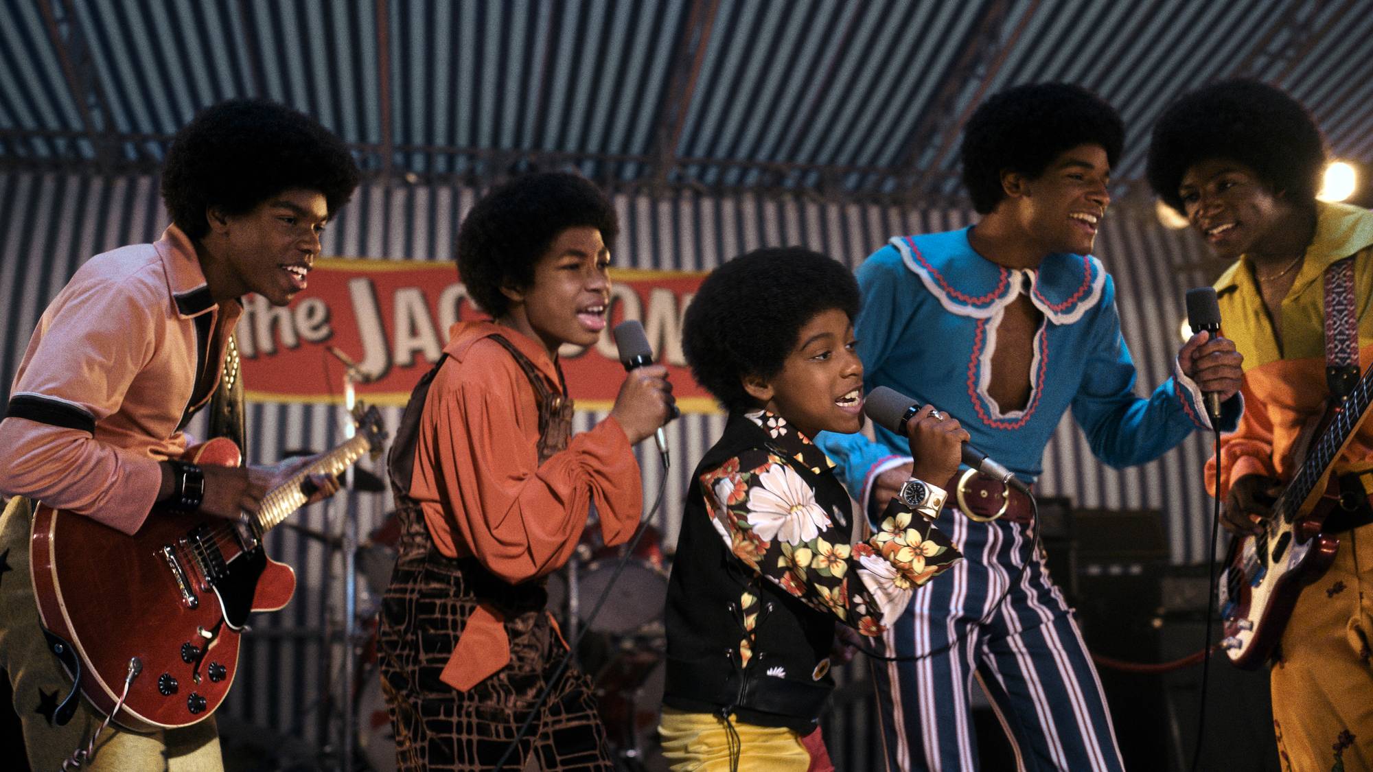 Fem gutter fra The Jackson 5 opptrer på en scene. Tre av guttene synger i mikrofoner. En spiller gitar.