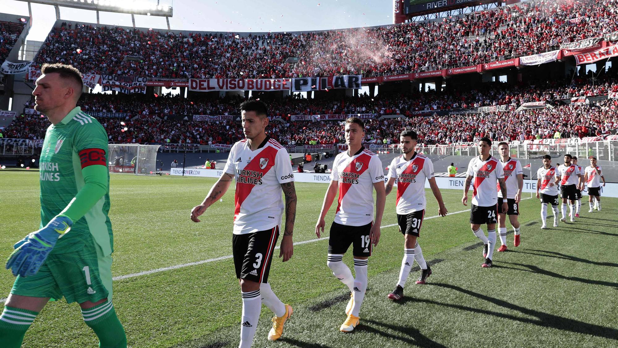 Fotballspillere fra River Plate går ut på banen på et fullsatt stadion før kamp. (Bildebeskrivelsen er laget av en KI-tjeneste)