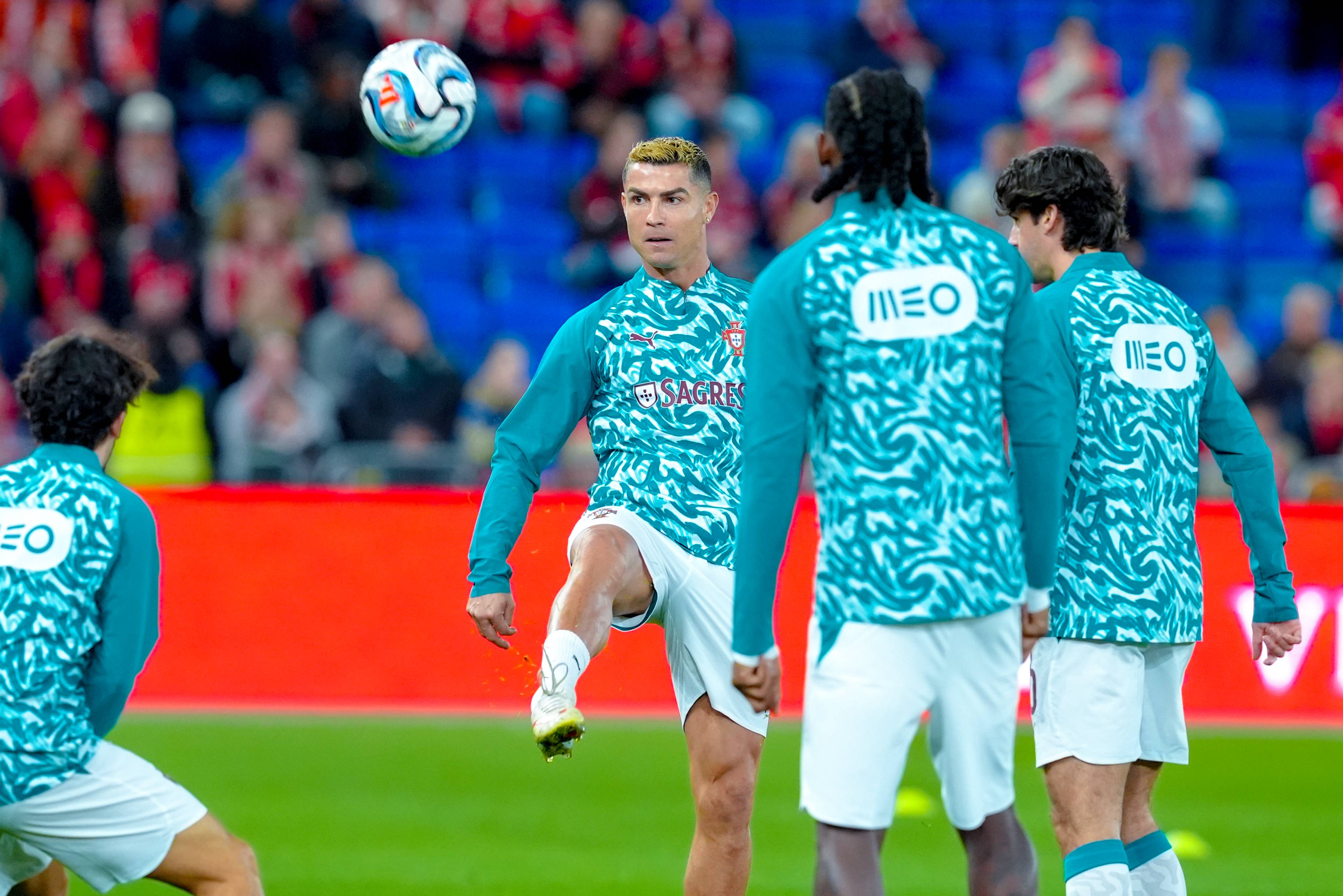 Cristiano Ronaldo og andre fotballspillere trener med ball på en fotballbane. (Bildebeskrivelsen er laget av en KI-tjeneste)