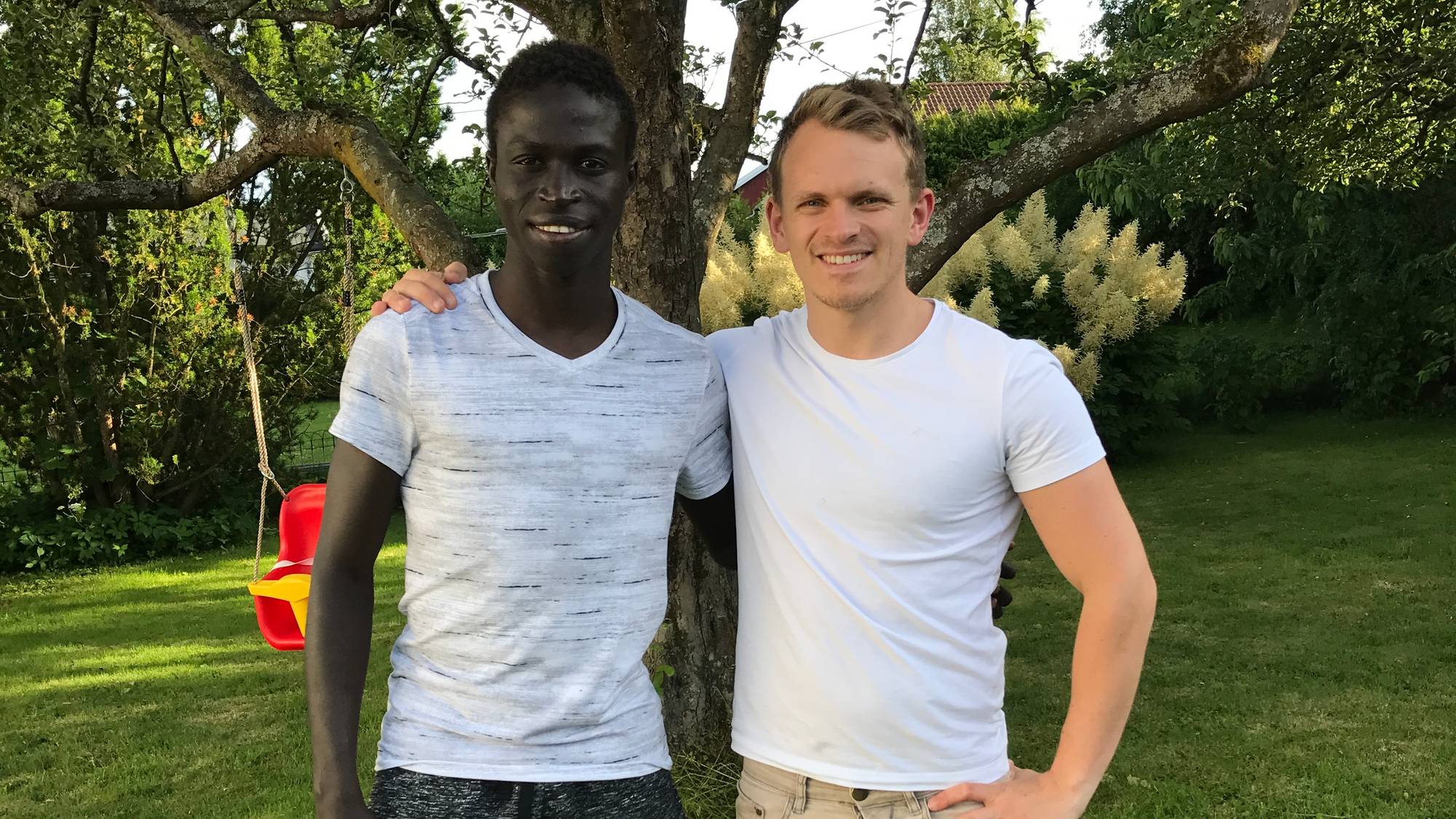 To menn som står på en gresskledd plass (Bildebeskrivelsen er laget av en KI-tjeneste)