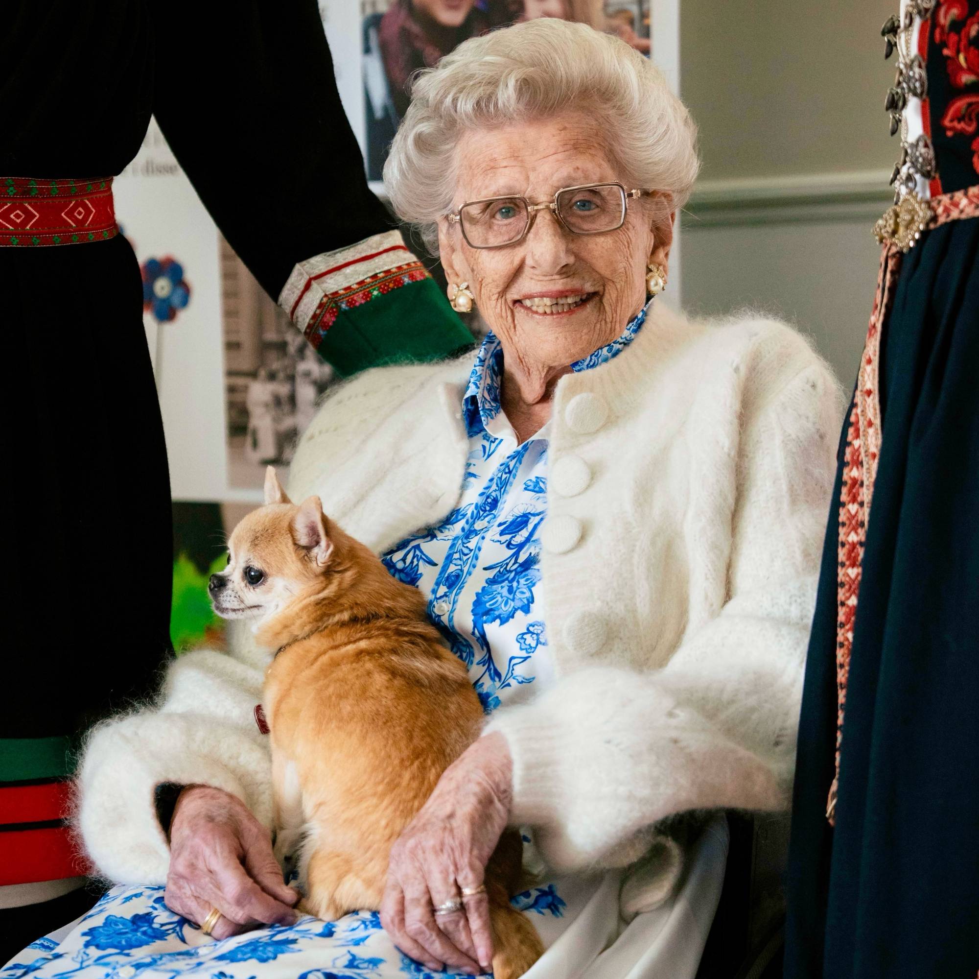 Prinsesse Astrid besøker Blindern og Vinderen Sanitetsforenings 100-årsjubileum, hun har hunden Wilma på fanget og er ikledd en hvit cardigan og en hvit og blå kjole