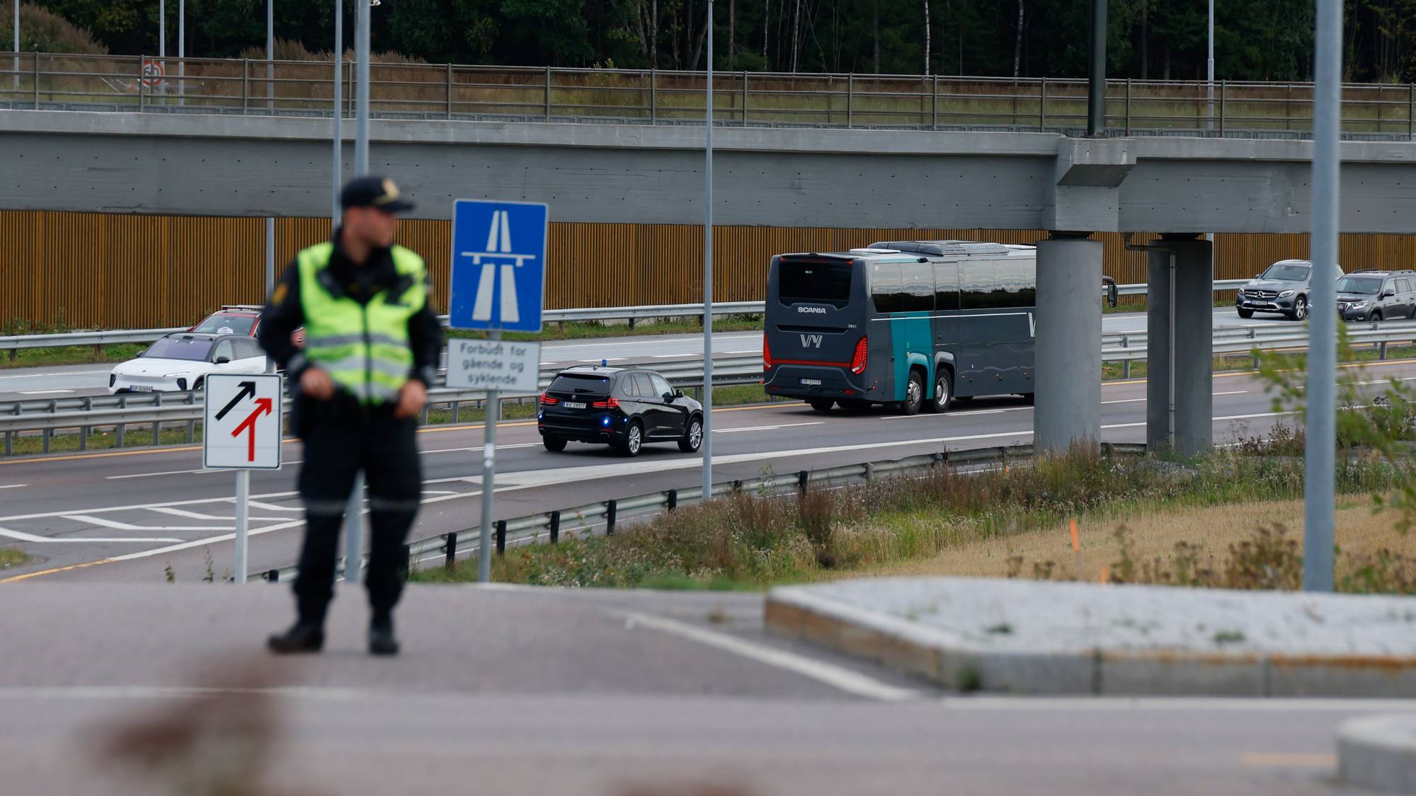 Politi i forgrunnen av bilde mens en kan se en bilkortesje i bakgrunnen på E6. 