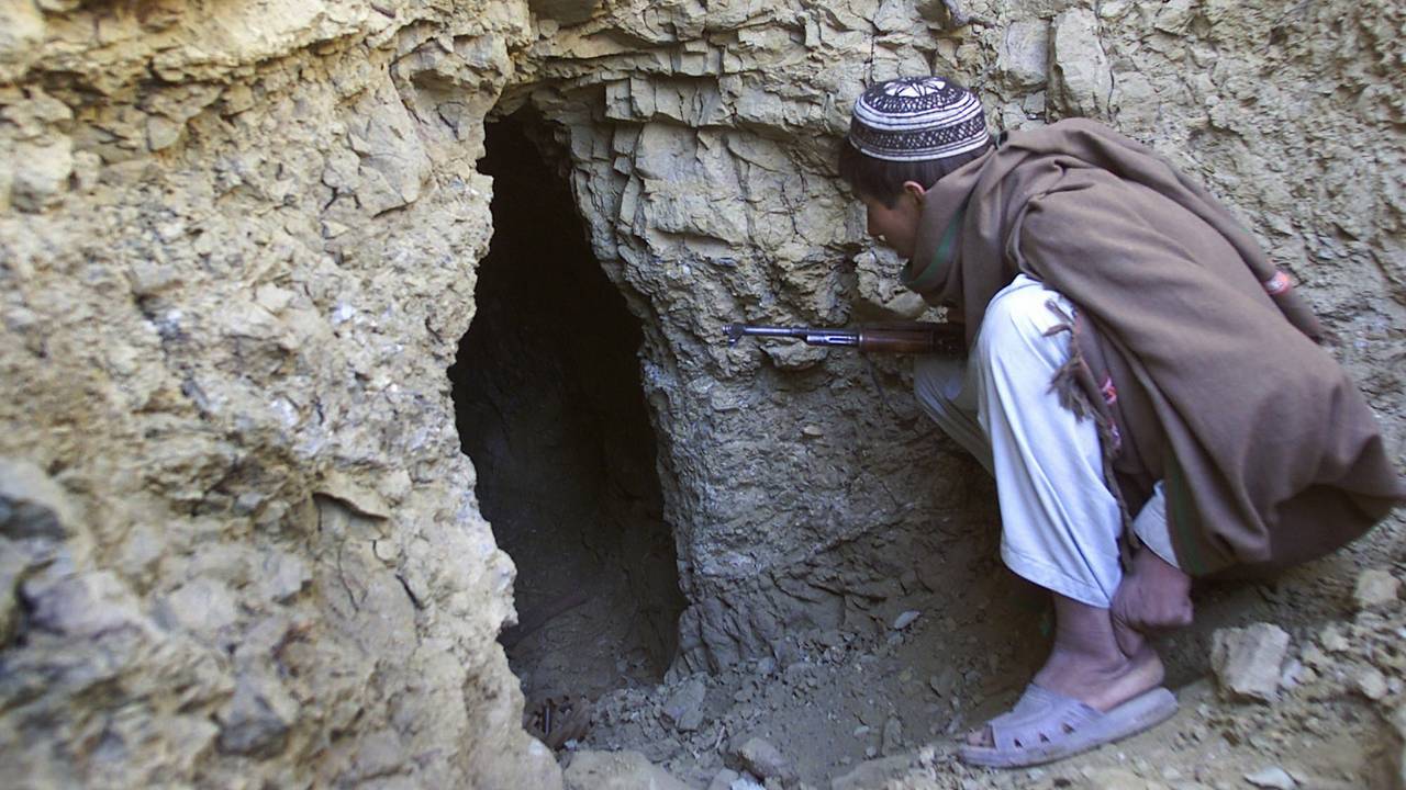 En afghansk mann som er mot Al Qaida titter i en hule i De hvite fjellene som terrorgruppen brukte til våpenlagring. En treningsleir lå like ved. Bildet er tatt 18. desember 2001.