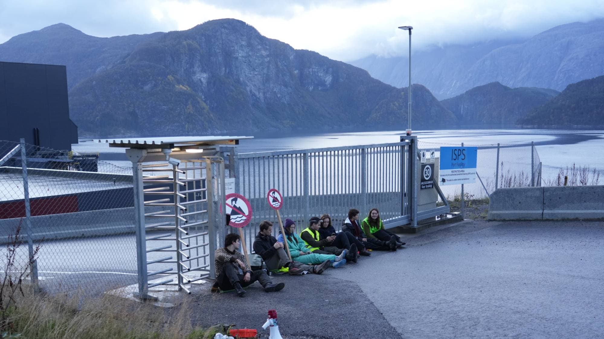 sju personar sit ved ein port