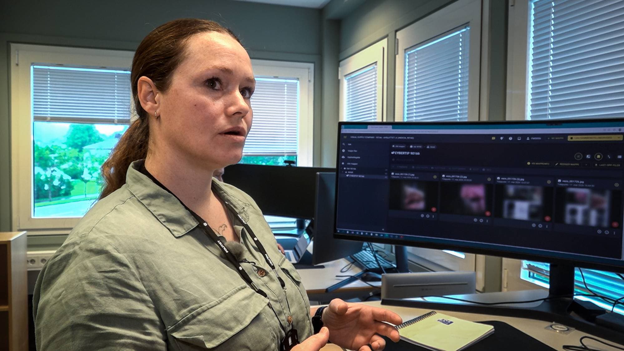 Kvinne med grønn skjorte og nøkkelkort rundt halsen jobber med PC-er