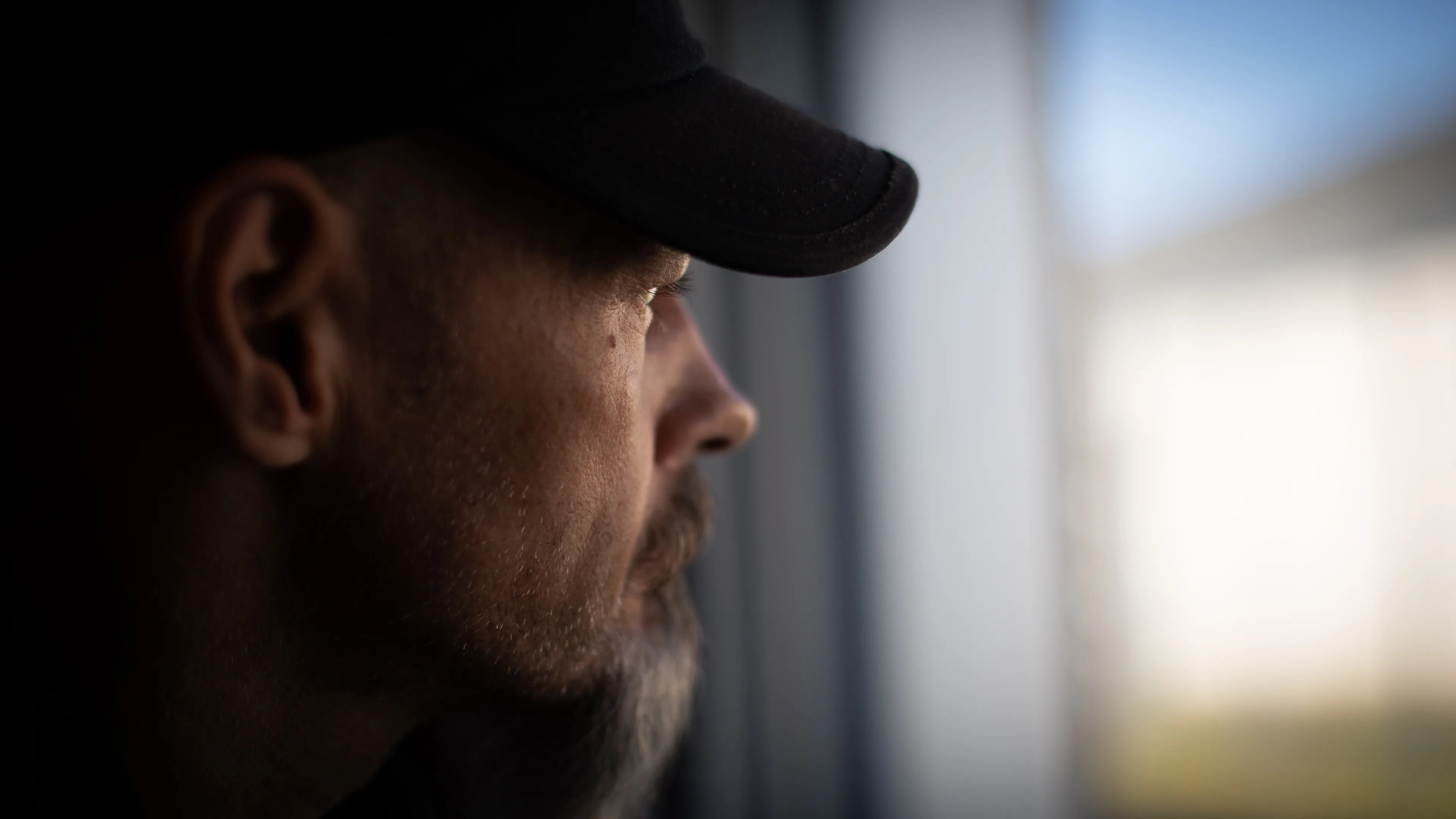 en mann med caps og skjegg ser ut av et vindu