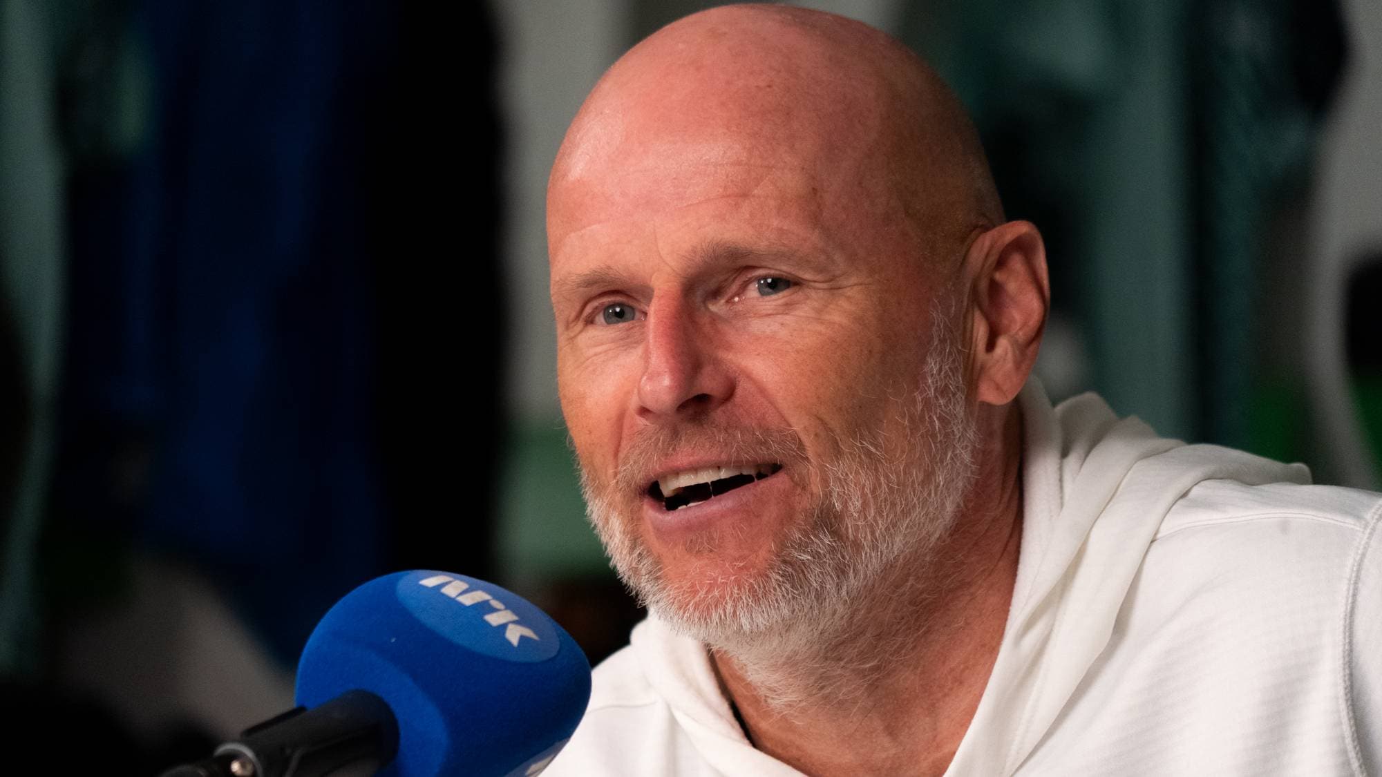 Ståle Solbakken snakker inn i en NRK-mikrofon under en pressekonferanse. (Bildebeskrivelsen er laget av en KI-tjeneste)