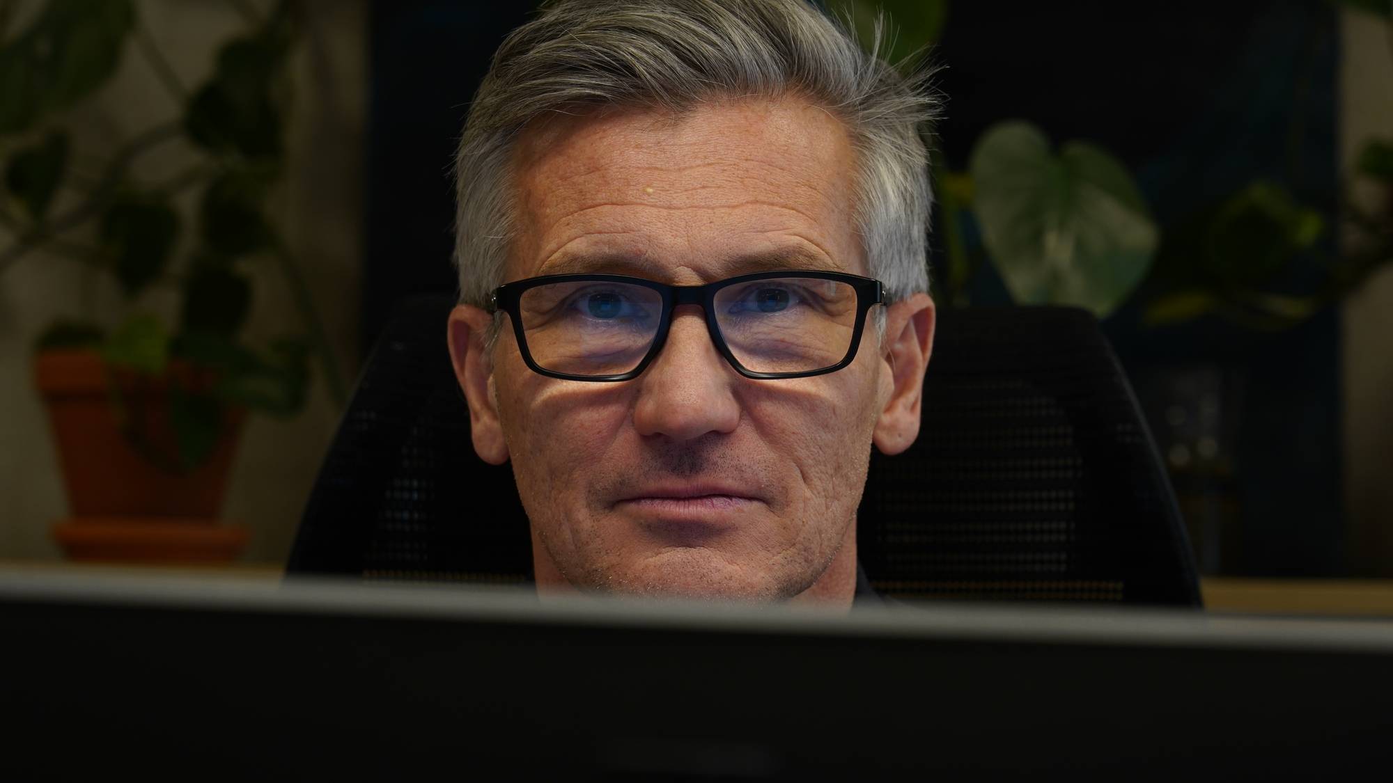 Bjørn Erik Thon ser inn i kameraet. Han sitter bak en PC-skjerm