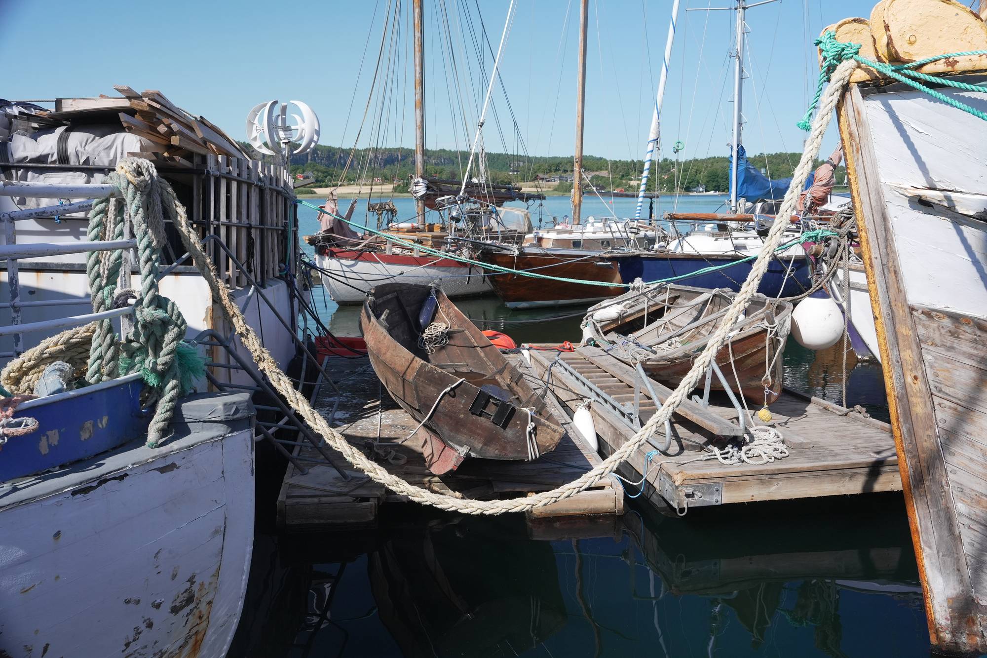 Flere seilbåter og andre fartøy er fortøyd sammen.