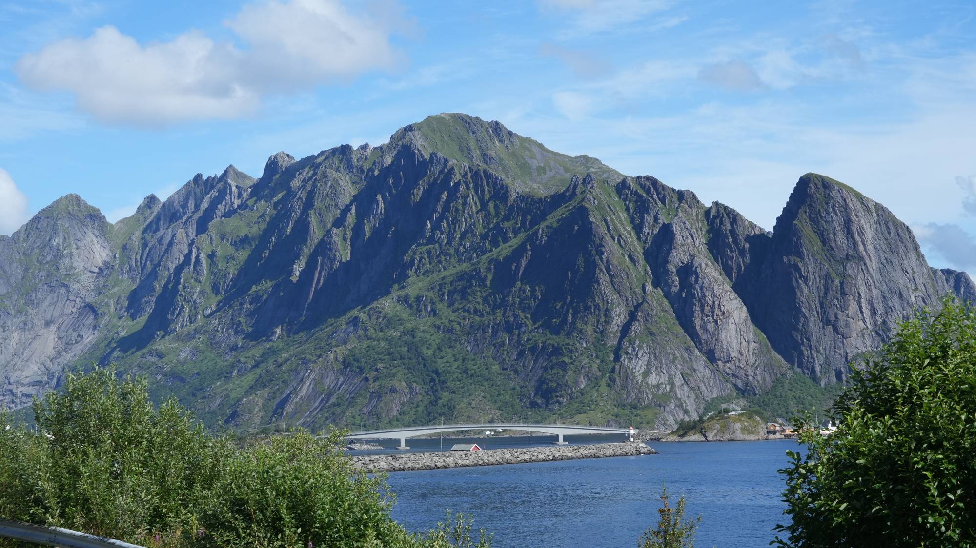 en innsjø med en bro og fjell i bakgrunnen (Bildebeskrivelsen er laget av en KI-tjeneste)
