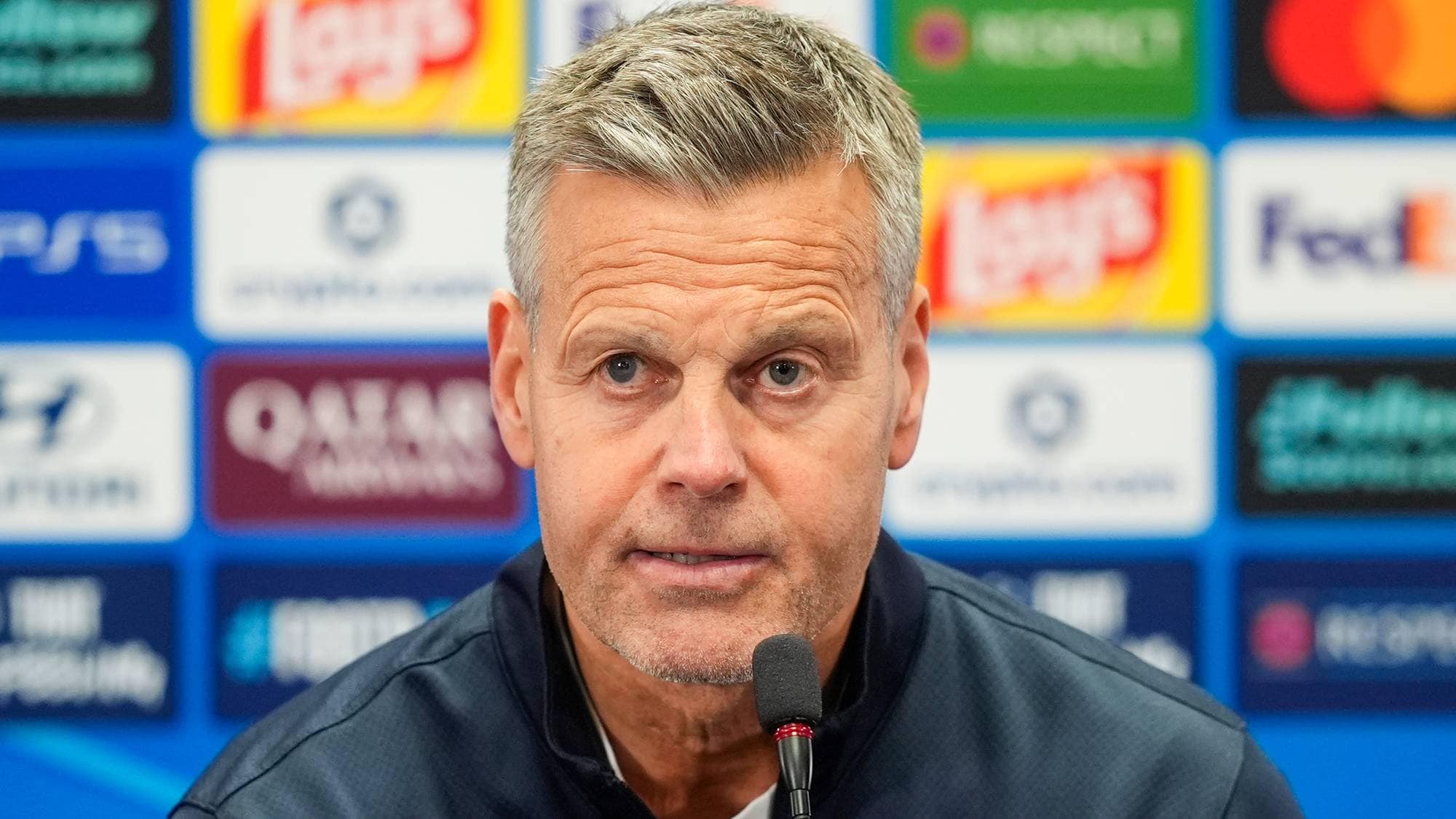 Kjetil Knutsen foran en bakgrunn med sponsorlogoer under en pressekonferanse. (Bildebeskrivelsen er laget av en KI-tjeneste)