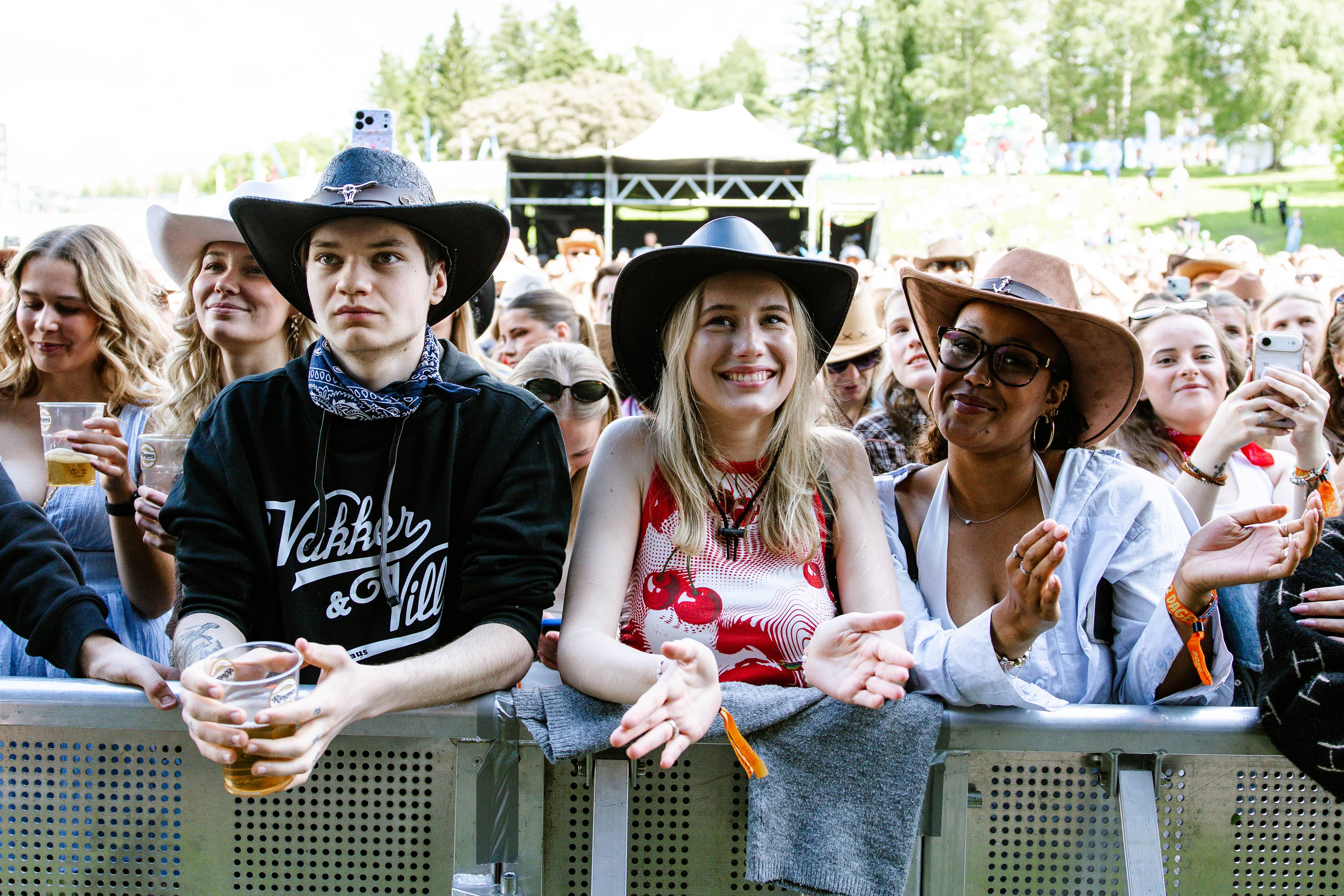 Bildet viser publikum på en konsert. Flere av dem har på seg cowboy-hatter