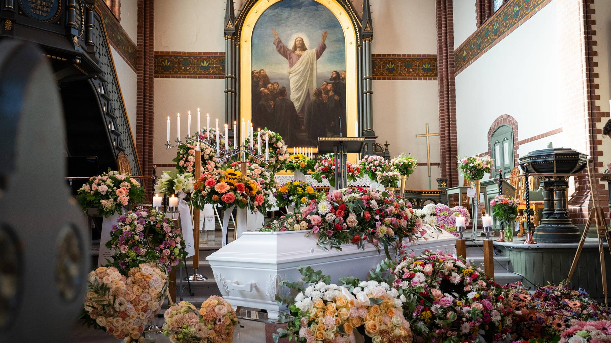flere blomster oppå en hvit grav i kirken