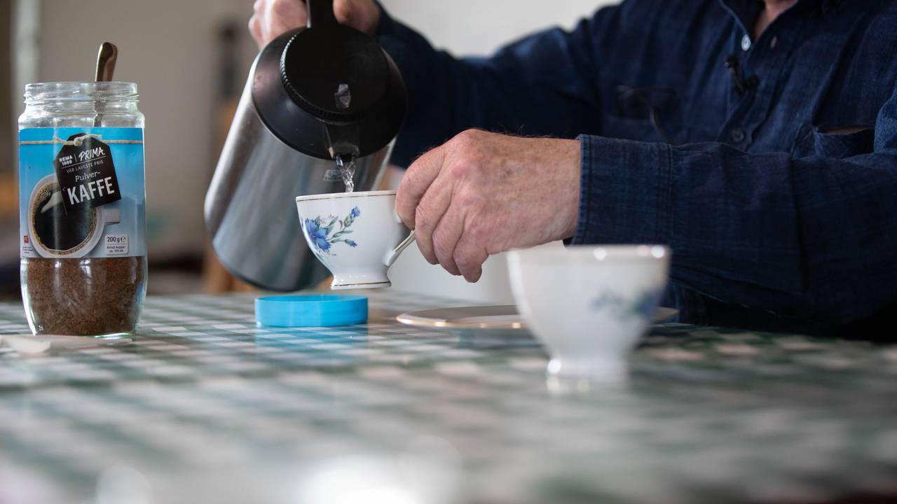 Varmt vann renner fra en kanne ned i en kaffeekopp med blå blomster