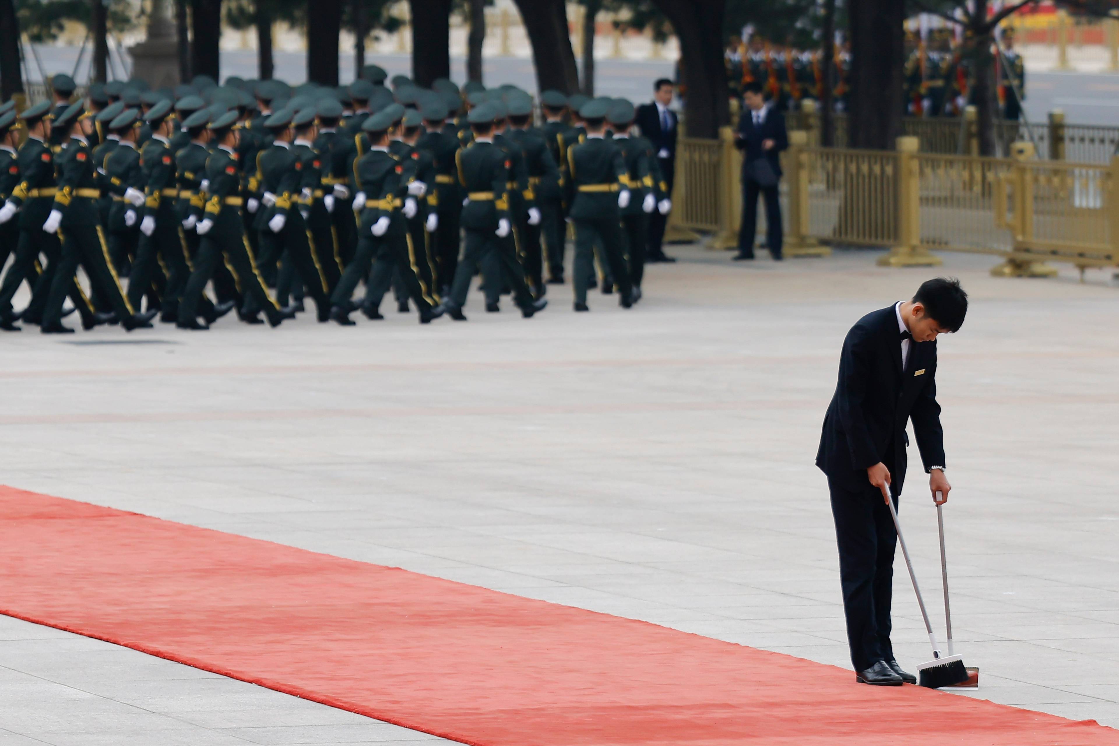 En kinesisk tjenestemann feier den røde løperen før Kinas president Xi Jinping skal ta imot Vladimir Putin,