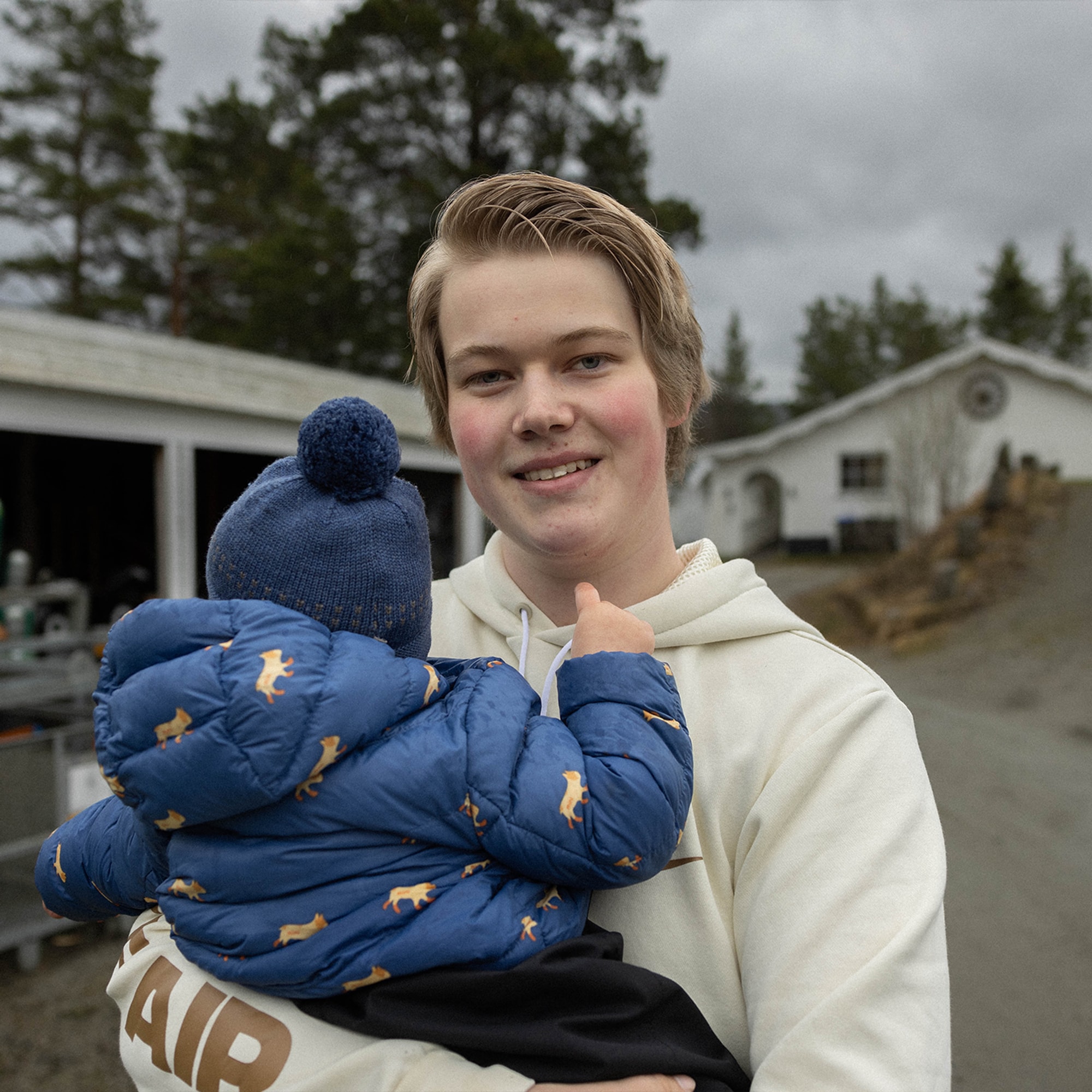 Bilde av Kjetil sammen med sønnen ikledd en blå vinterdress foran huset sitt på Geilo. 