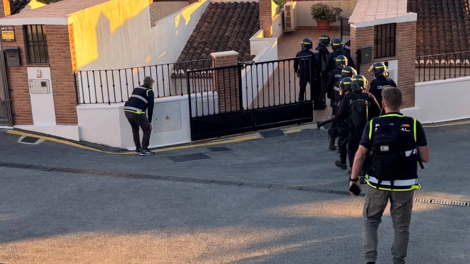 Bildet viser politifolk som tar seg inn i en bolig i Spania. 