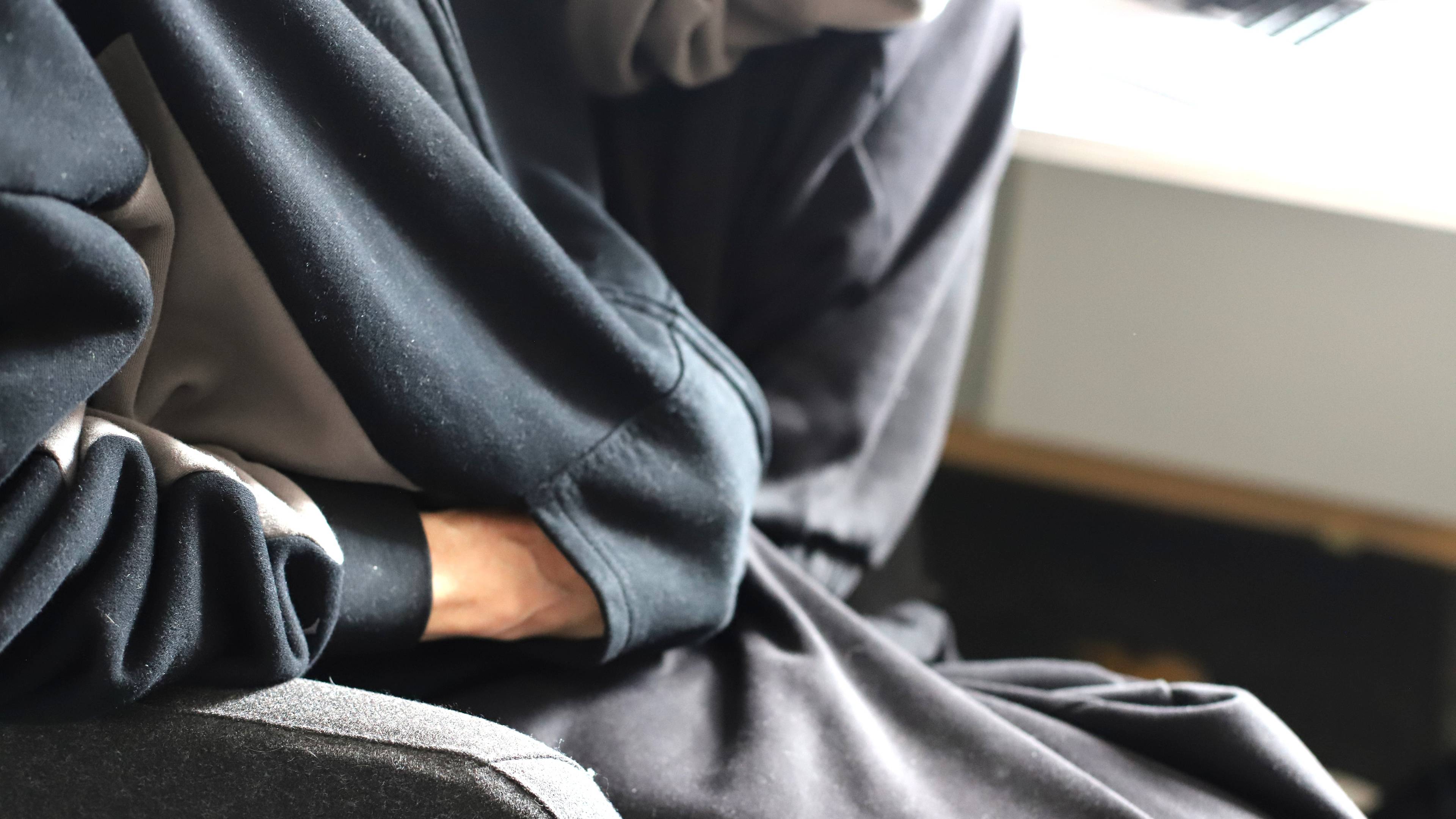 Bilde av en som sitter med en sort joggedrakt på en stol.