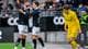 Foto: Carina Johansen / NTB To fotballspillere i mørke drakter feirer, mens en motspiller i gult går forbi på banen. (Bildebeskrivelsen er laget av en KI-tjeneste)