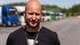 Christian Nygaard-Monsen / NRK Bald man with beard wearing black t-shirt.
He wears a lanyard with "Toll Customs" written on it.
In the background, there are parked trucks.
The photo is taken outdoors on a sunny day. (Bildebeskrivelsen er laget av en KI-tjeneste)