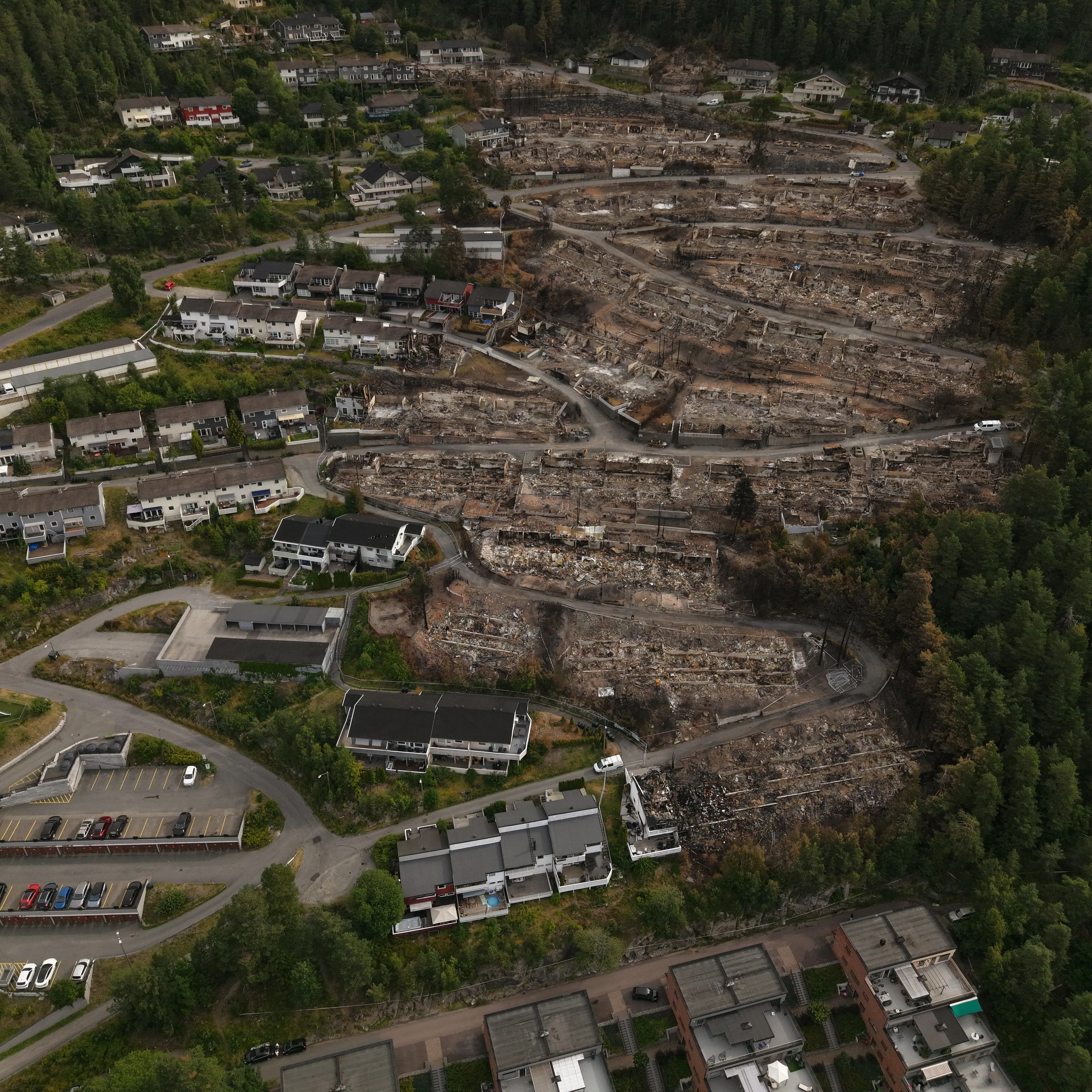 Flyfoto av et boligområde preget av store brannskader og ødelagte tomter etter brann. (Bildebeskrivelsen er laget av en KI-tjeneste)