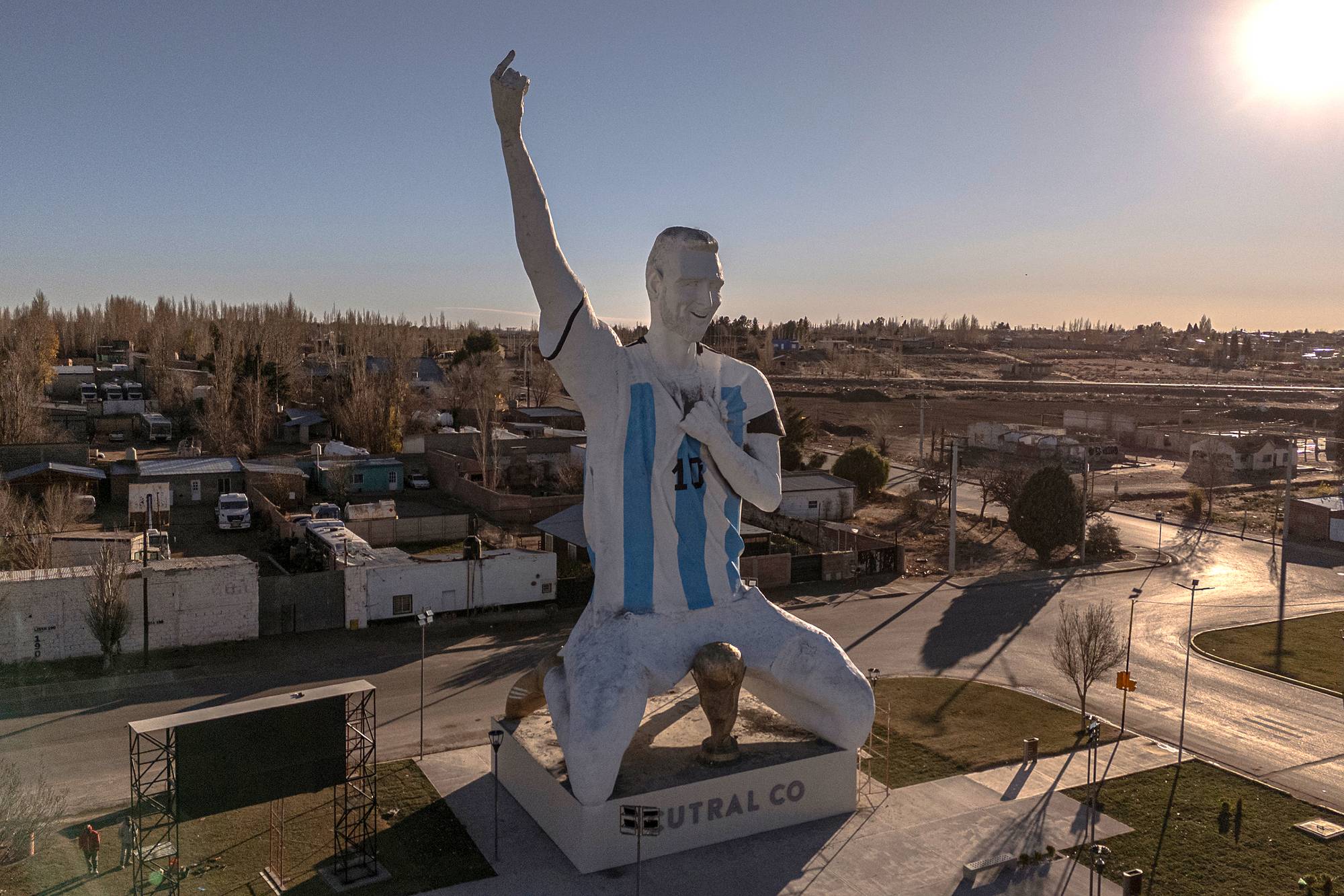 Stor statue av Lionel Messi i Argentina-drakt knelende foran en VM-pokal i et åpent bylandskap. (Bildebeskrivelsen er laget av en KI-tjeneste)