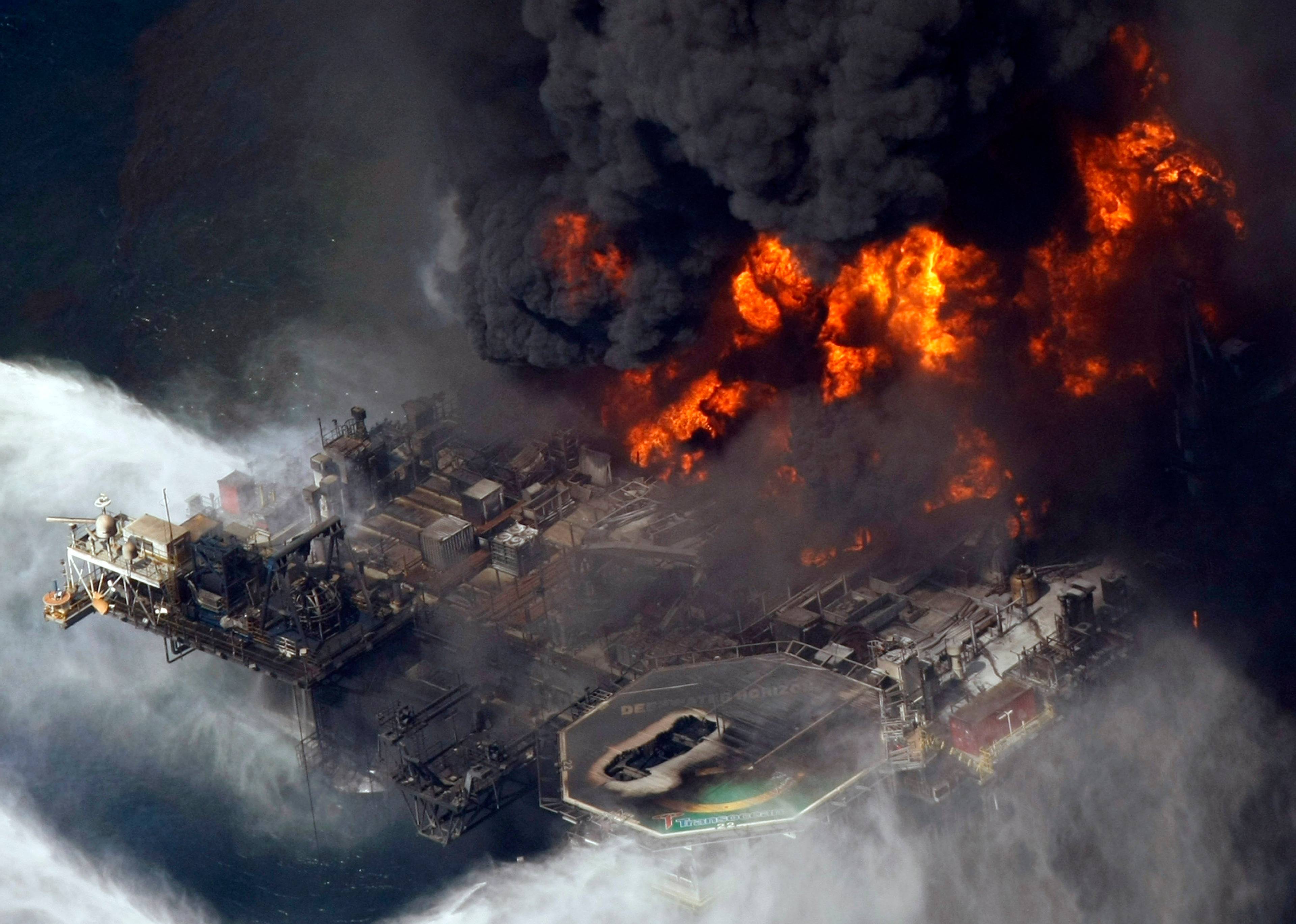 En røykplume stiger fra branner på BPs offshore oljerigg Deepwater Horizon i Mexicogulfen den 21. april 2010. Flammene er kraftig oransje og røyken helt svart. Bildet er tatt ovenfra og man ser bare deler av plattformen.