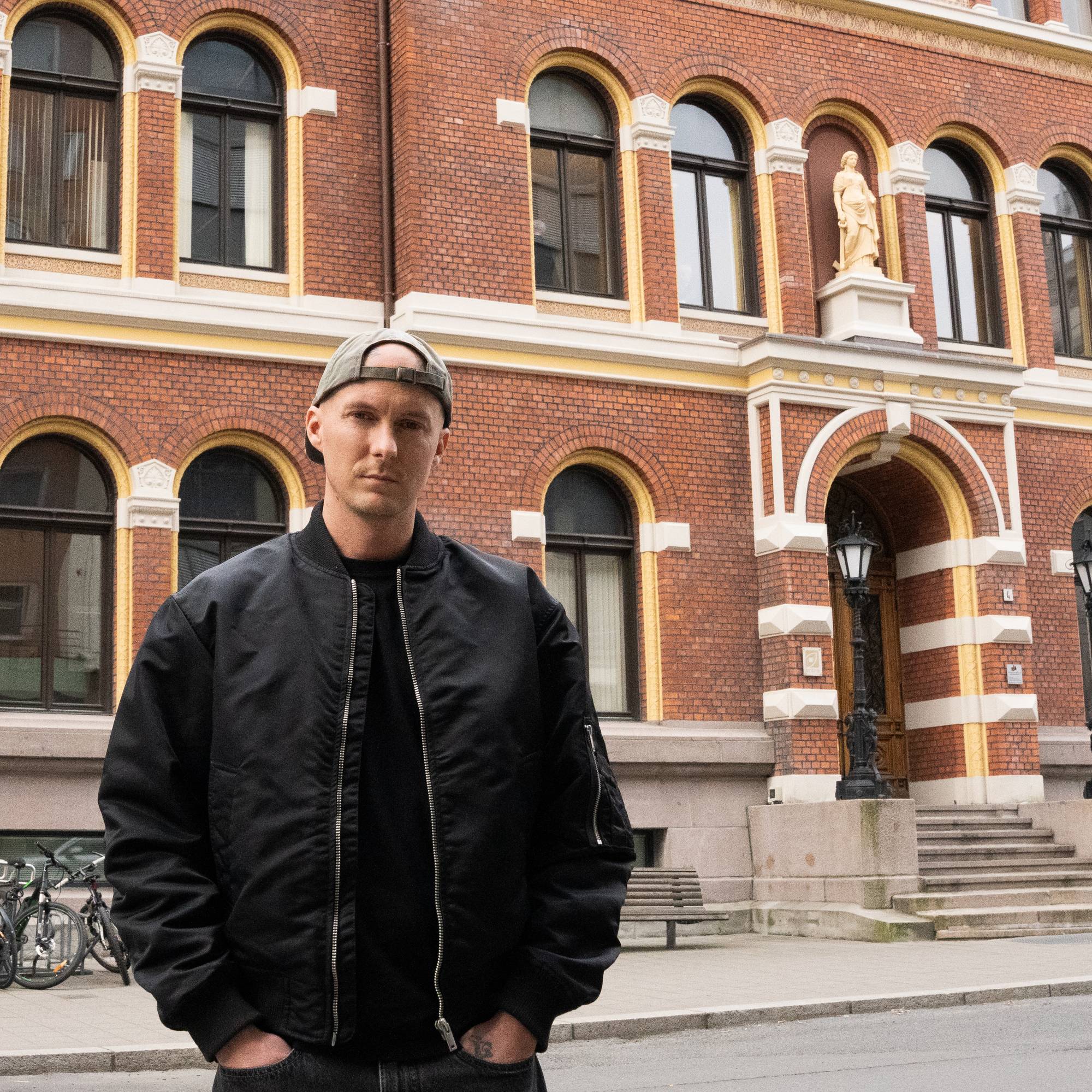 En mann på fortauet foran en stor bygning.