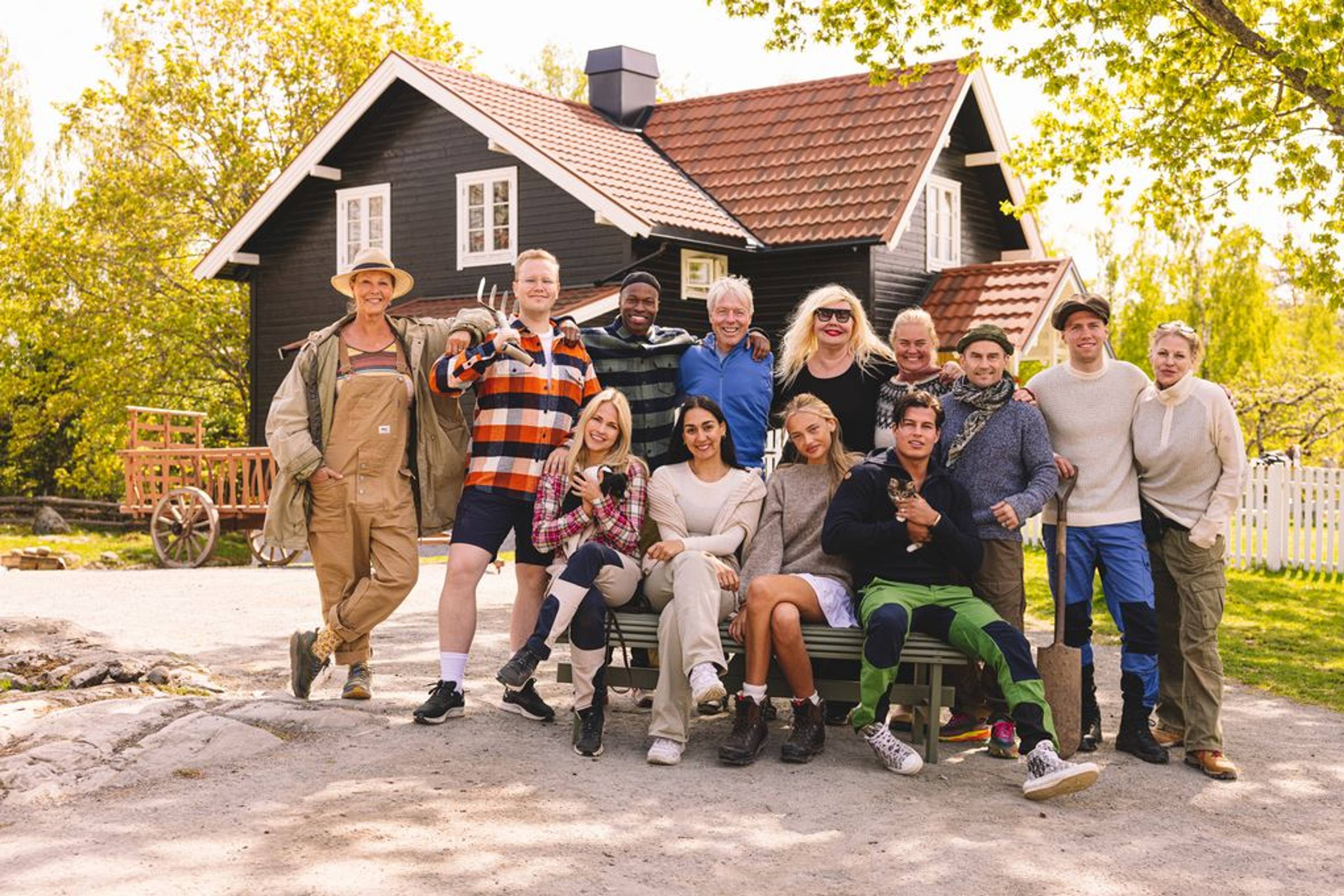 Ein gjeng står oppstilt foran eit brunt hus på eit tun.