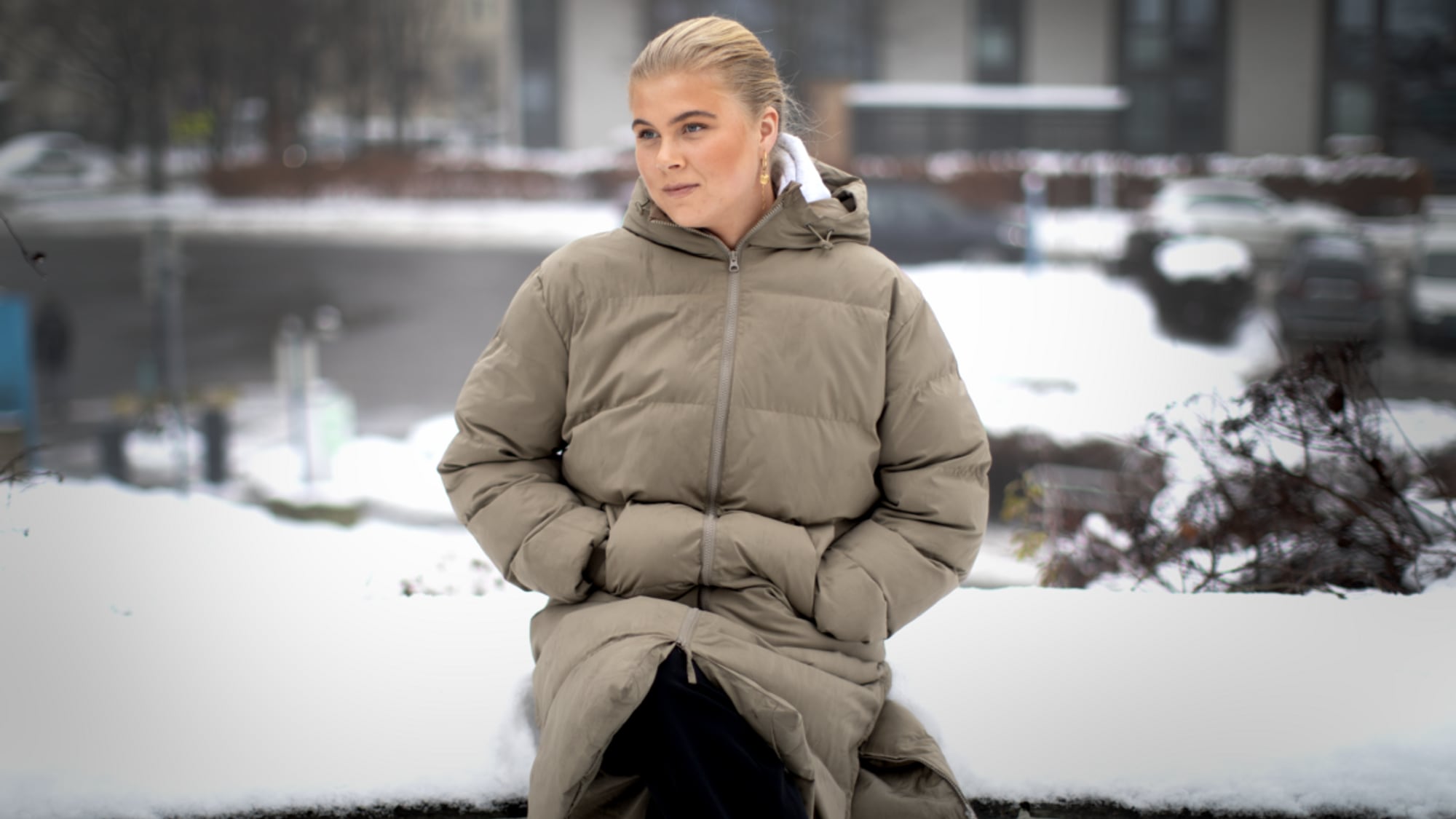 Foto av skribenten som sitter på en benk i snøen. Hun har på seg en grønn jakke og har blondt hår.