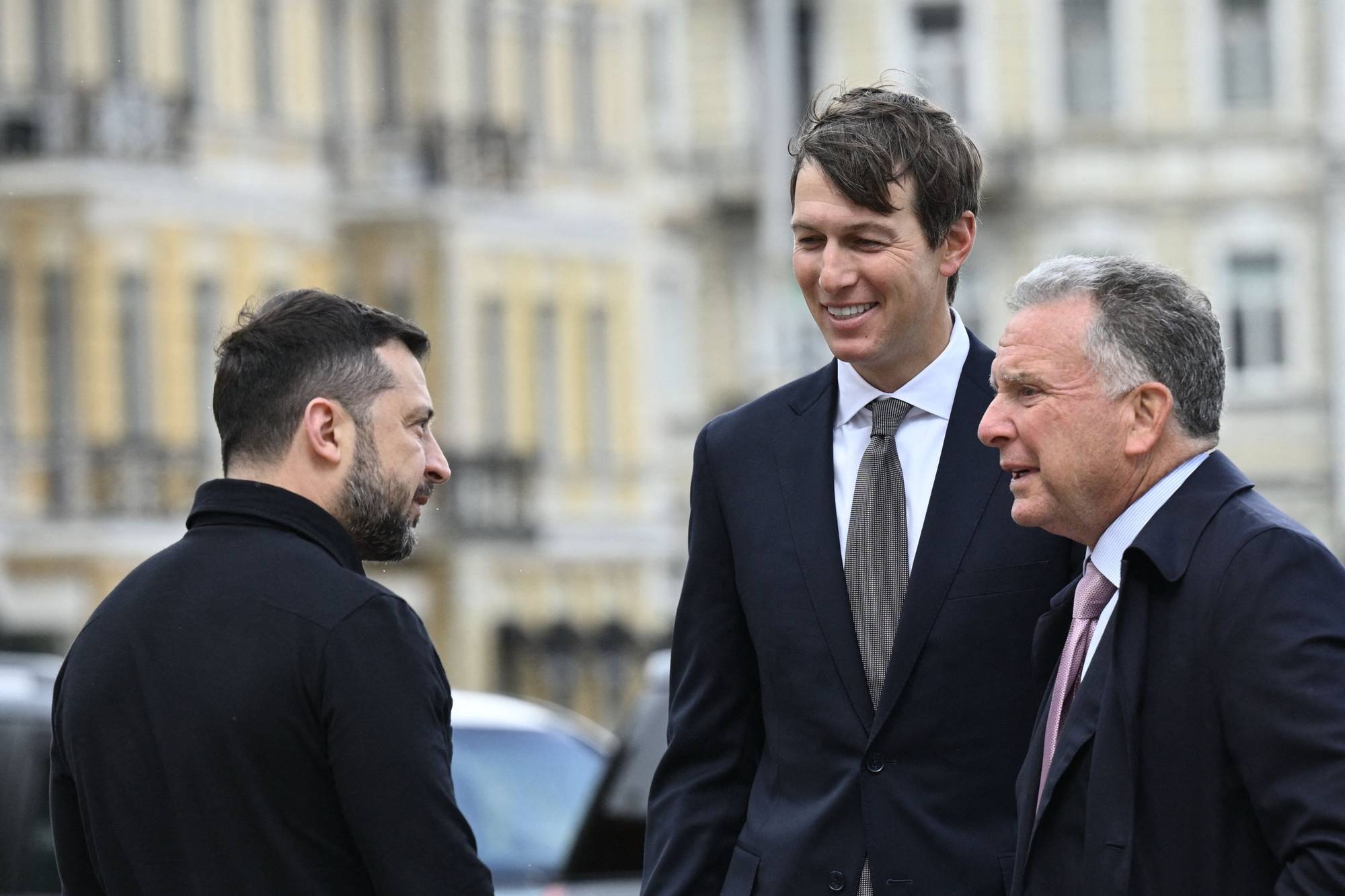 Volodymyr Zelenskyj i samtale med Jared Kushner og en annen mann i dress utendørs. (Bildebeskrivelsen er laget av en KI-tjeneste)