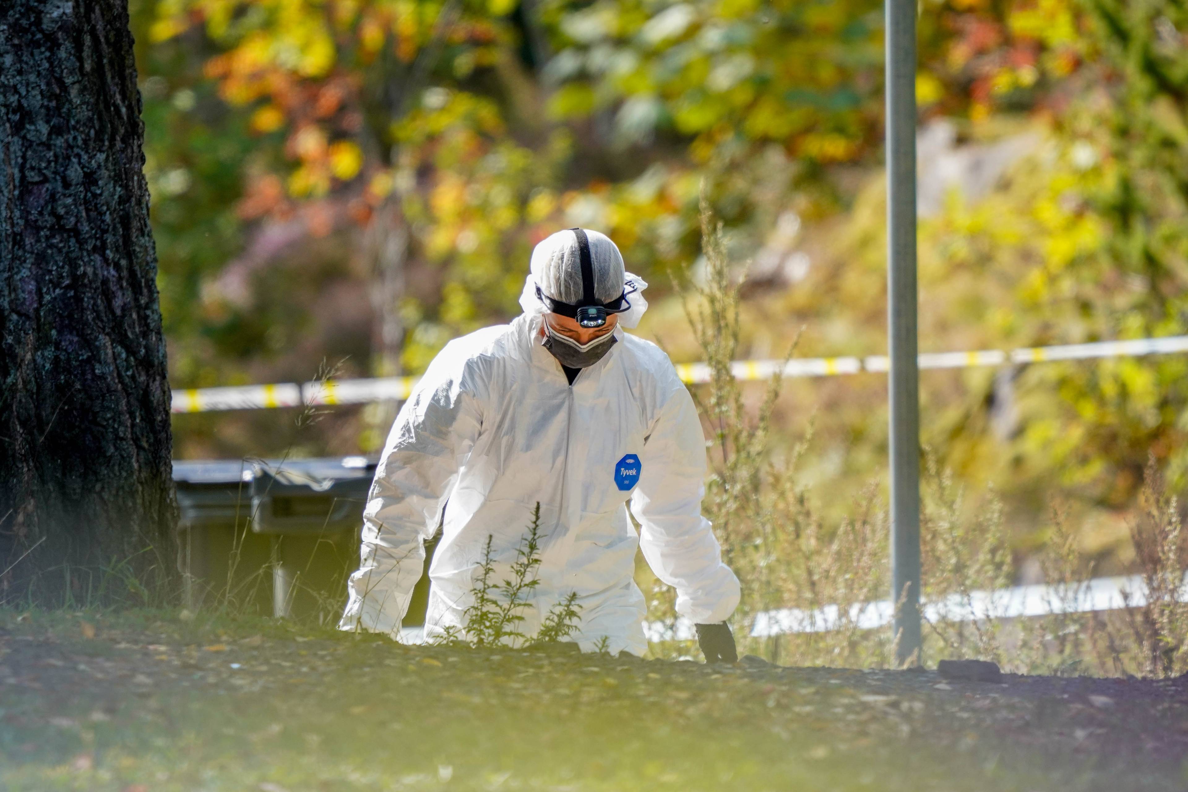 En person i hvit krimeknikerdrakt går på en grønn bakke.