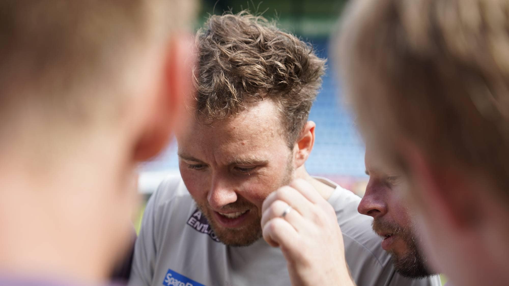 Emil Iversen ser ned på en telefon med folk rundt seg