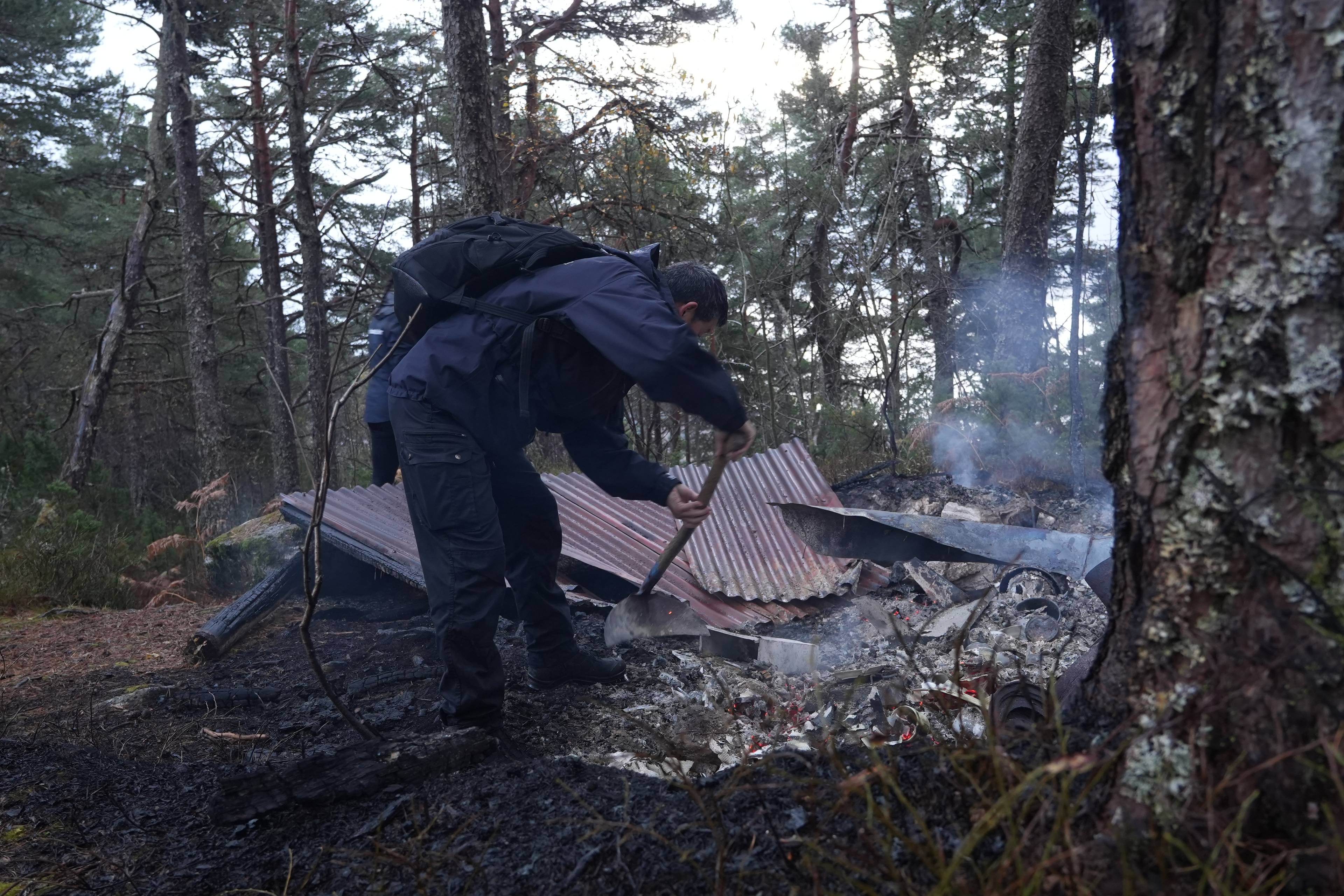 Person bruker spade i aske etter brann i et skogsområde.