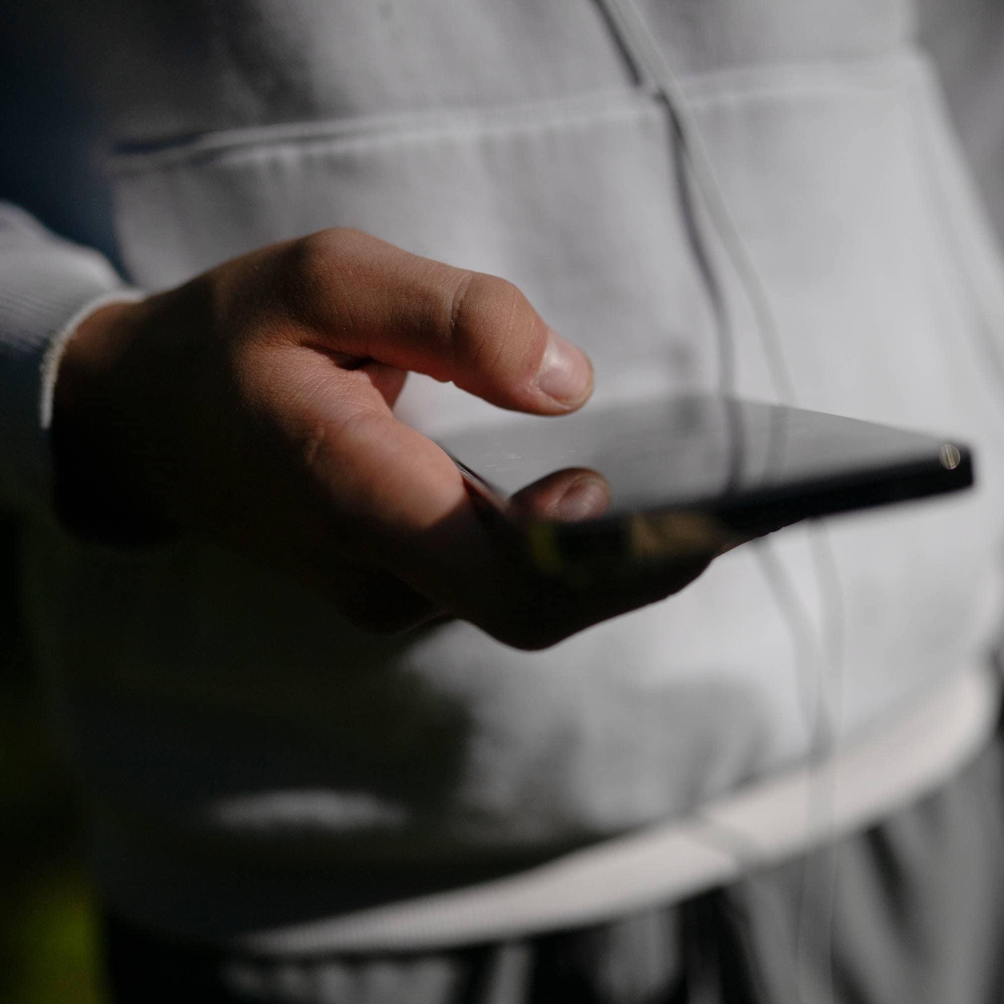 Person i lys hettegenser holder en smarttelefon i hendene. (Bildebeskrivelsen er laget av en KI-tjeneste)