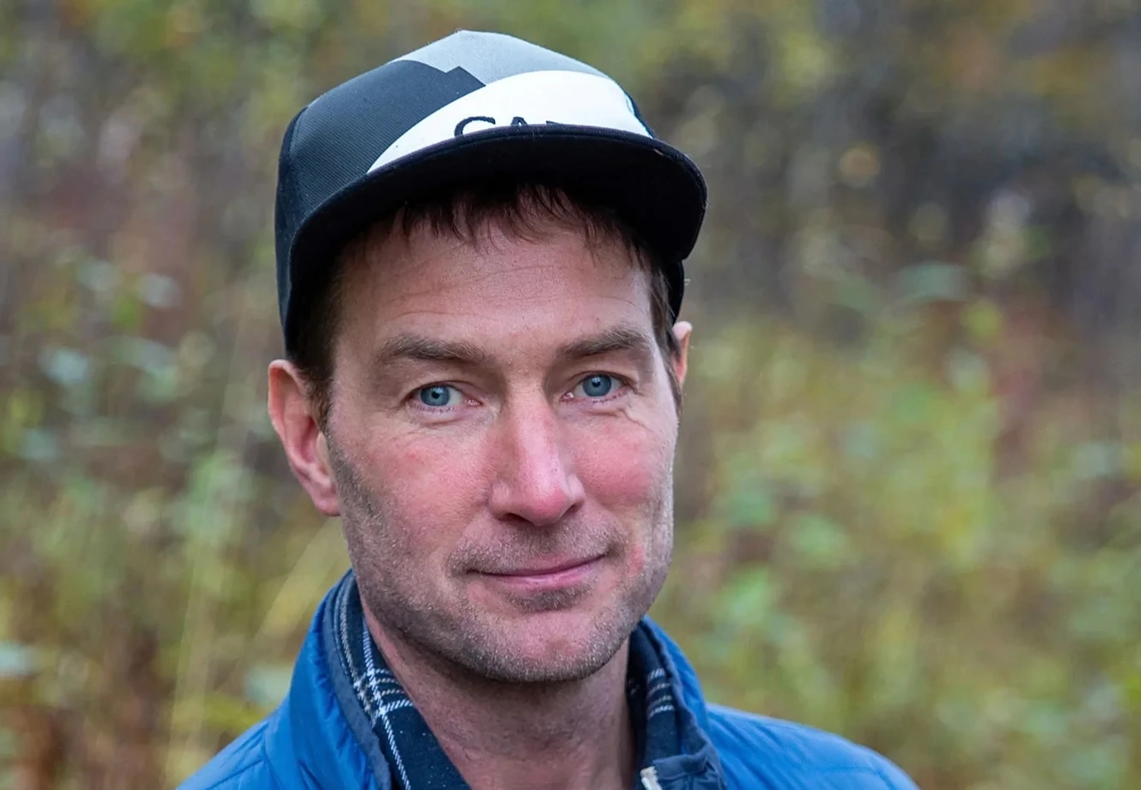 En mann med caps ute i grønn natur