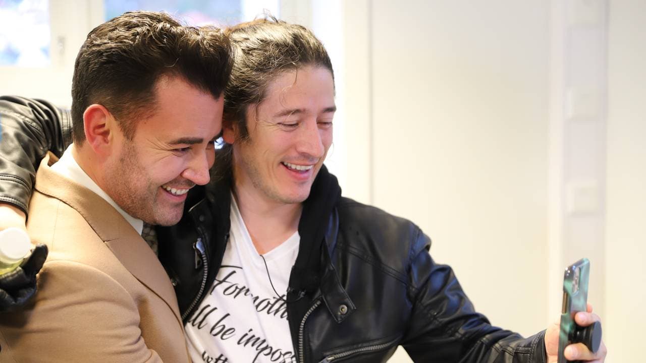 John Erik Aarsheim og broren Juan Jimenez smiler mens de ser inn i en telefon og tar selfie.