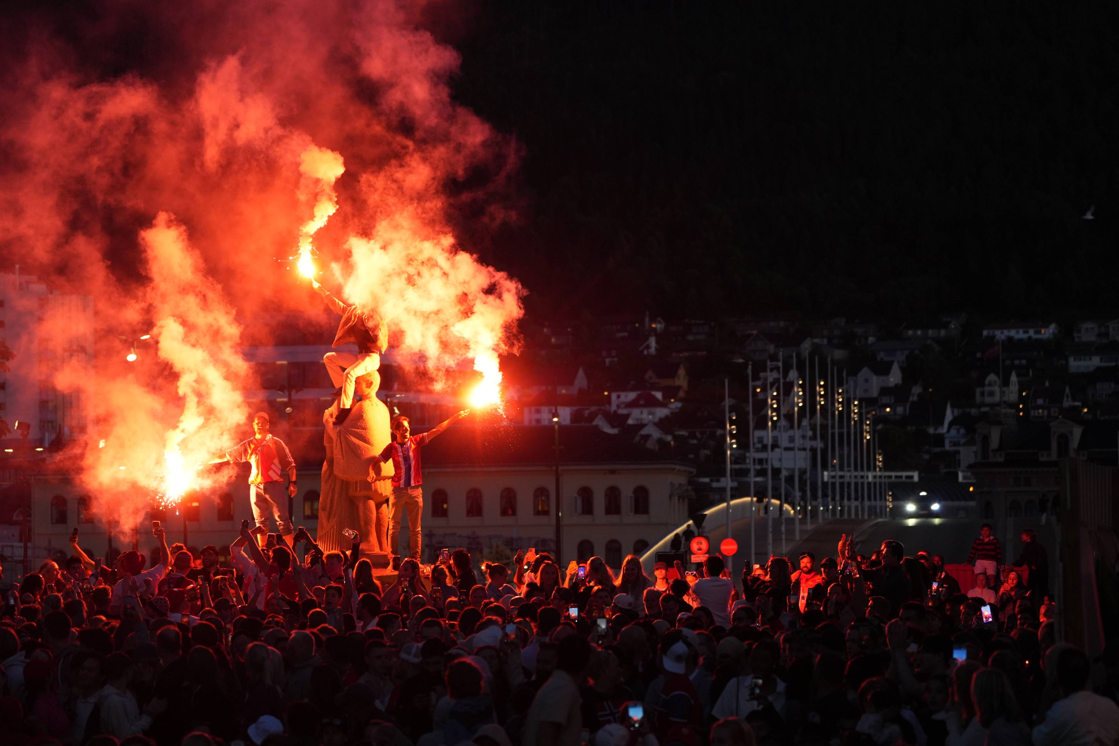 Folkemengde med bluss rundt en statue i Bergen sentrum om kvelden. (Bildebeskrivelsen er laget av en KI-tjeneste)