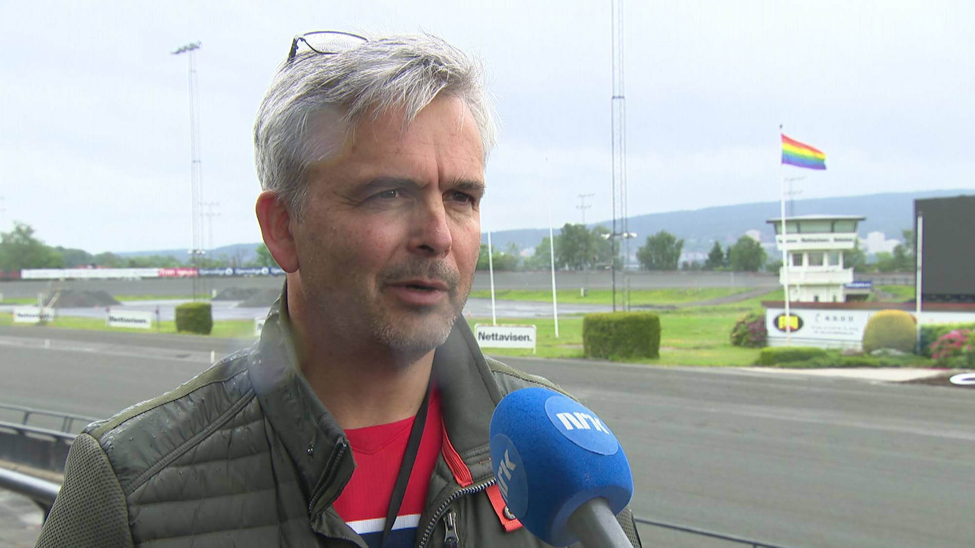 Mann intervjues foran en travbane
