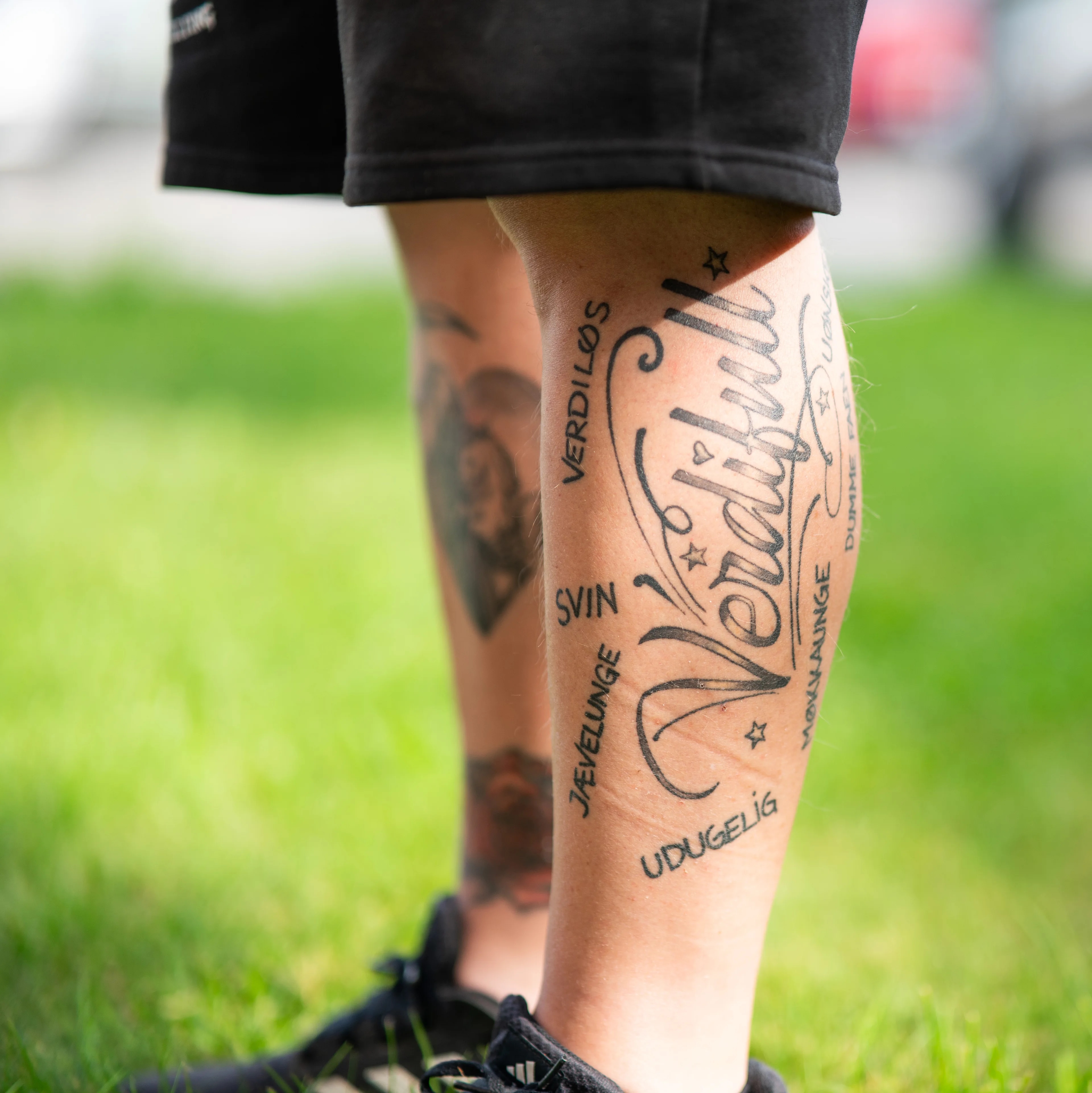 Nærbilde av underben med tatovering av ordet Verdifulle omgitt av andre ord. (Bildebeskrivelsen er laget av en KI-tjeneste)