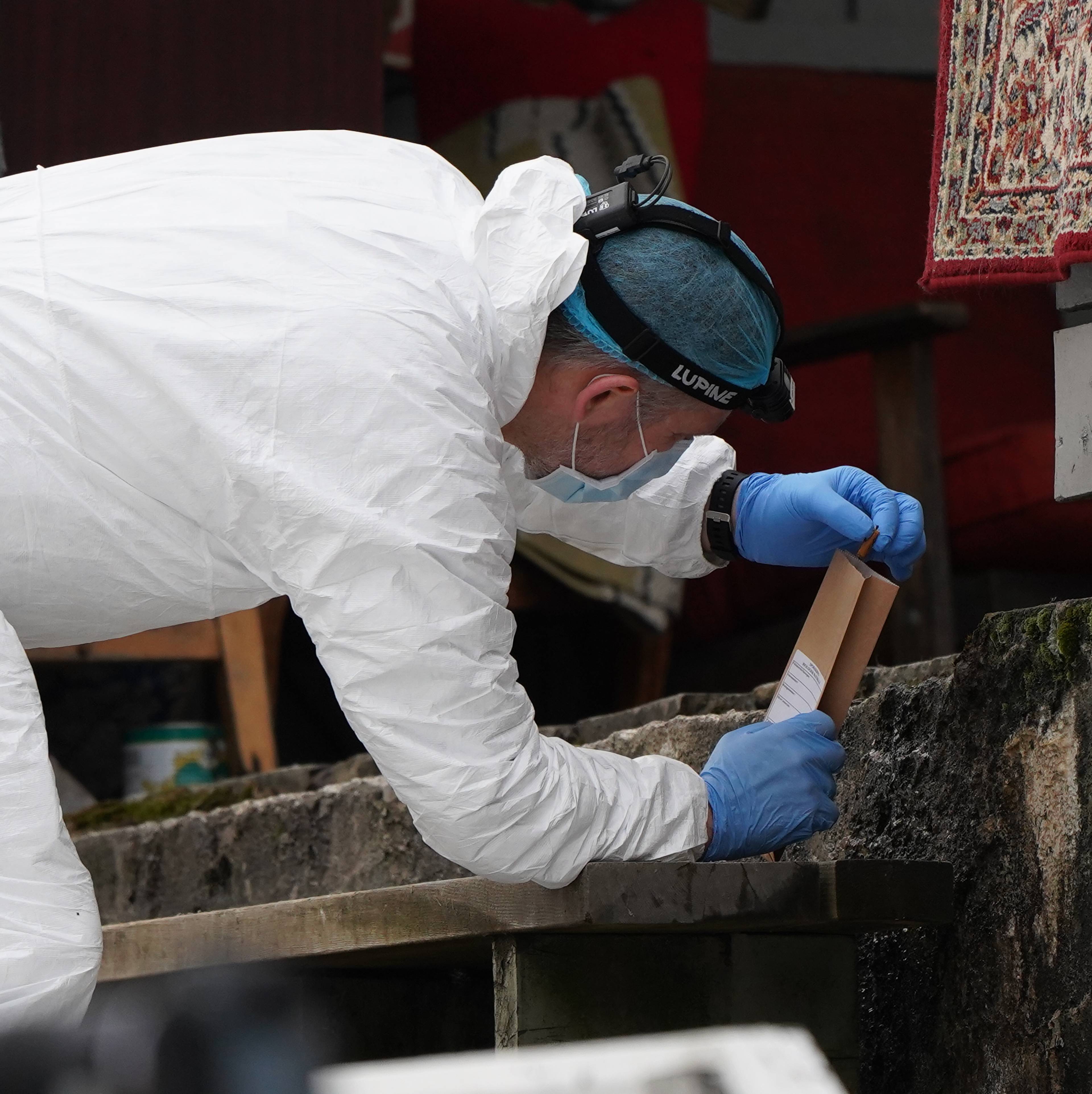en mann iført en hvit laboratoriefrakk og hansker som plukker en sigarettsneip.
