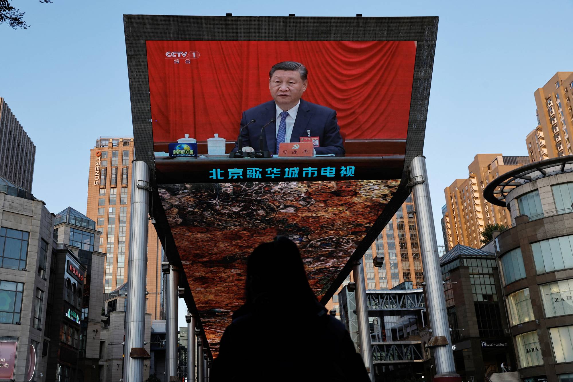 Stor skjerm viser Xi Jinping i Beijing-bydel, sett fra ryggen av en forbipasserende person. (Bildebeskrivelsen er laget av en KI-tjeneste)