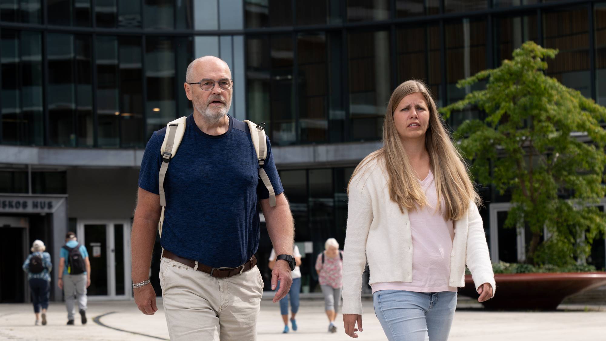 To personer som spaserer over en plass og snakker til hverandre