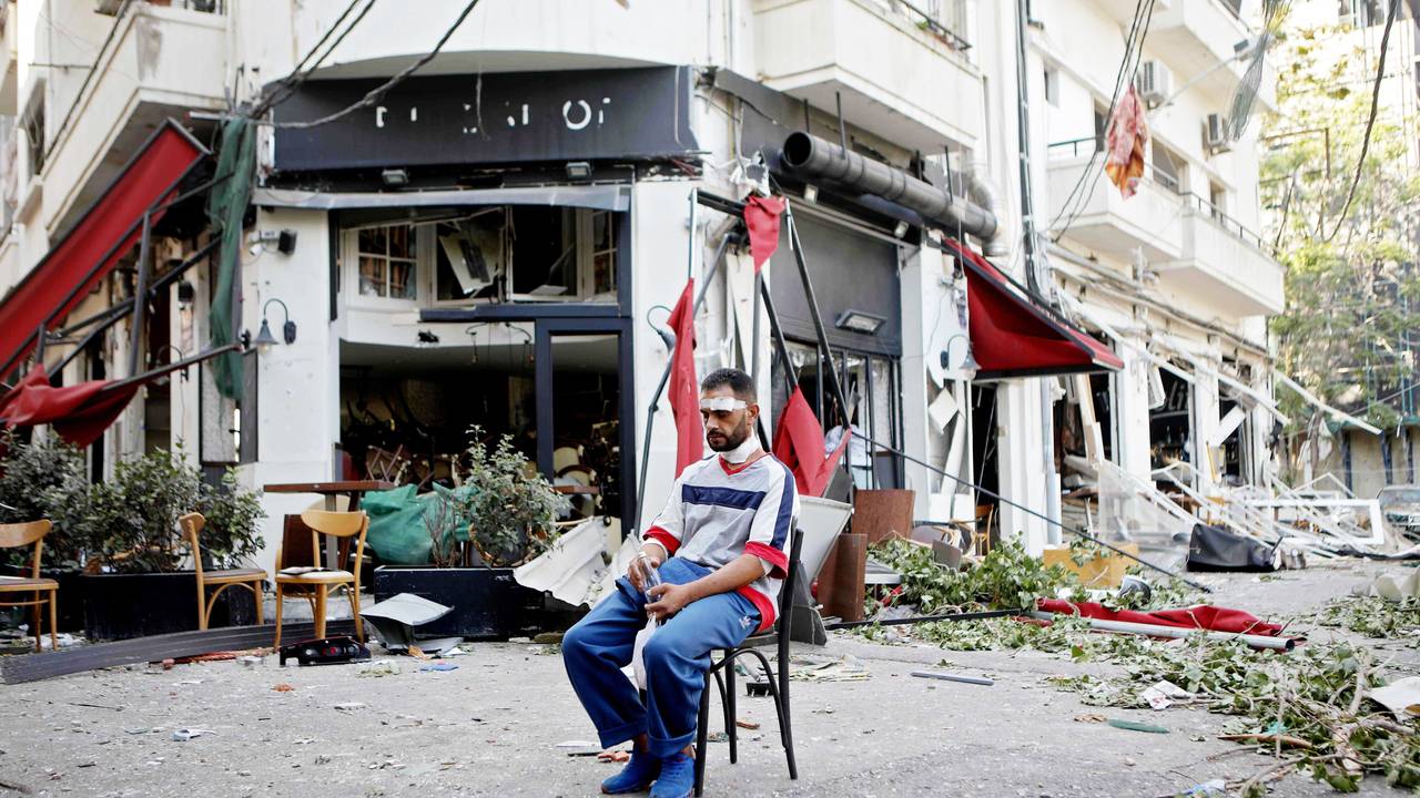 En skadet mann sitter utenfor en ødelagt restaurant etter eksplosjonen