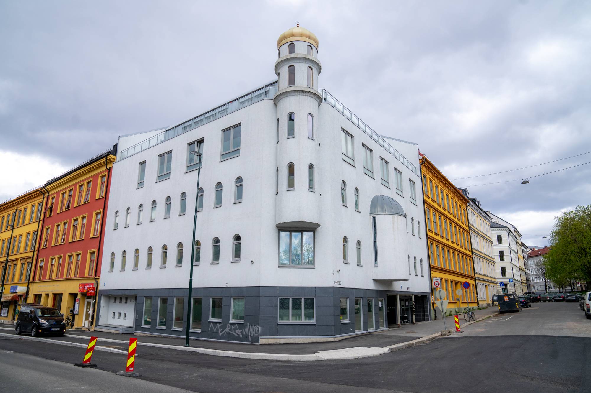 Hjørnet av en hvit murbygning med fire etasjer.